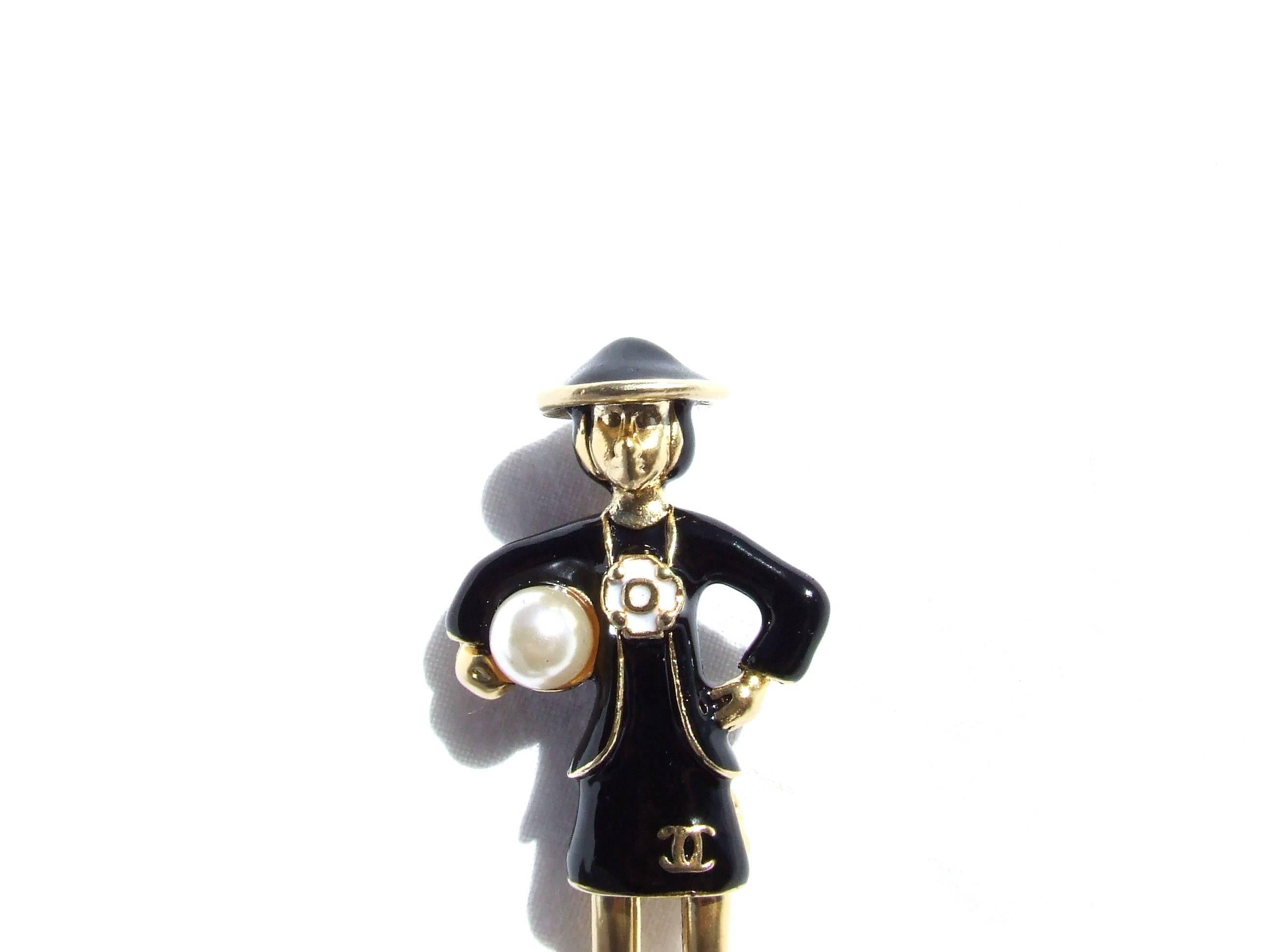 Beautiful Authentic CHANEL Brooch

Made of golden Metal, dress and hat in black Enamel

Represents Mademoiselle Coco Chanel in her black dress, holding a false pearl under her right arm

Camelia in the middle, and cc logo at the bottom of the