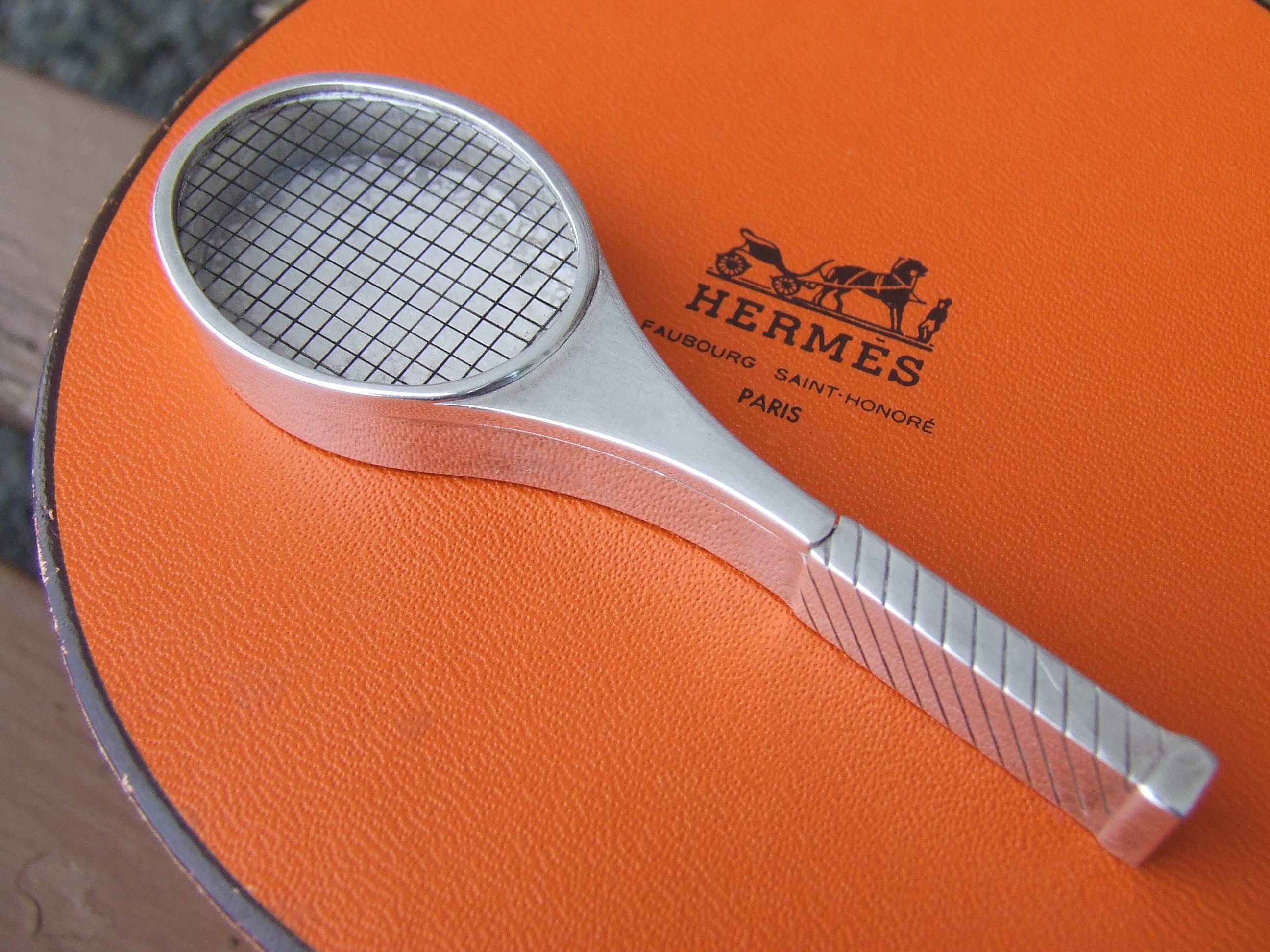 Rare and Collectible Authentic Hermès Pill Box

Tennis Racquet Shaped

Made in France

Made of silver-tone Metal

The lid is made of transparent plastic on which are drawn lines representing the ropes of the racquet

Opens by sliding the lid