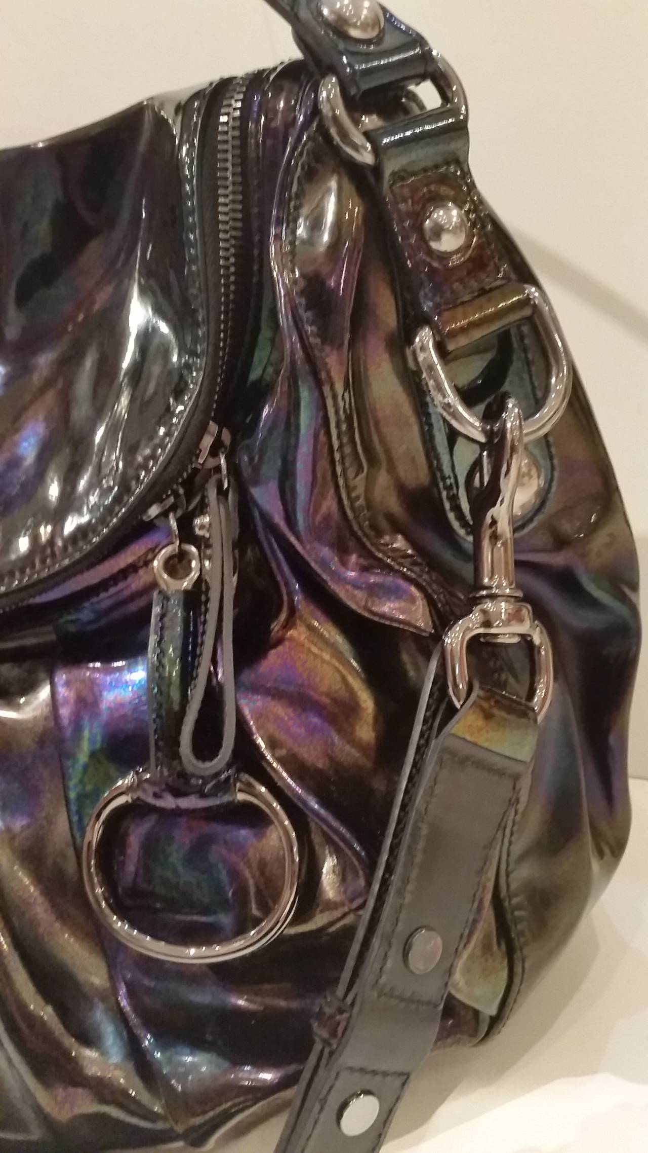 This Gucci Metallic Icon Bit Hobo Bag is made from metallic leather with a petrol spill finish. The bag has a zip fastening and features a carry handle together with a removable, adjustable shoulder strap. The metal work on the bag is silver in