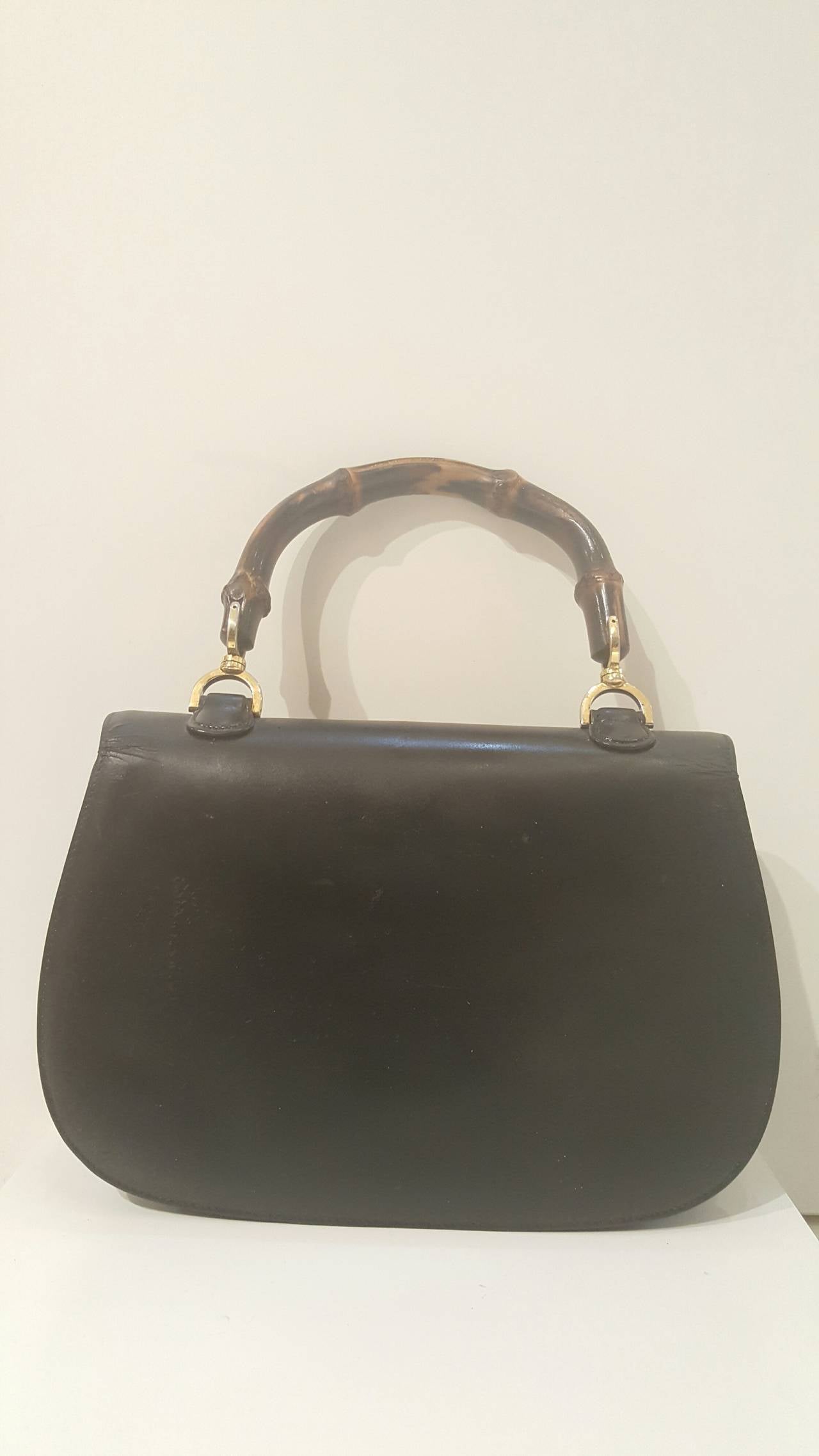 1980s Gucci Bamboo black leather handbag
GUCCI Vintage Leather Bamboo Top Handle Bag in Black. This stylish tote is crafted of black leather. The bag features a looping bamboo top handle, a frontal flap, brass hardware and a bamboo turn lock and