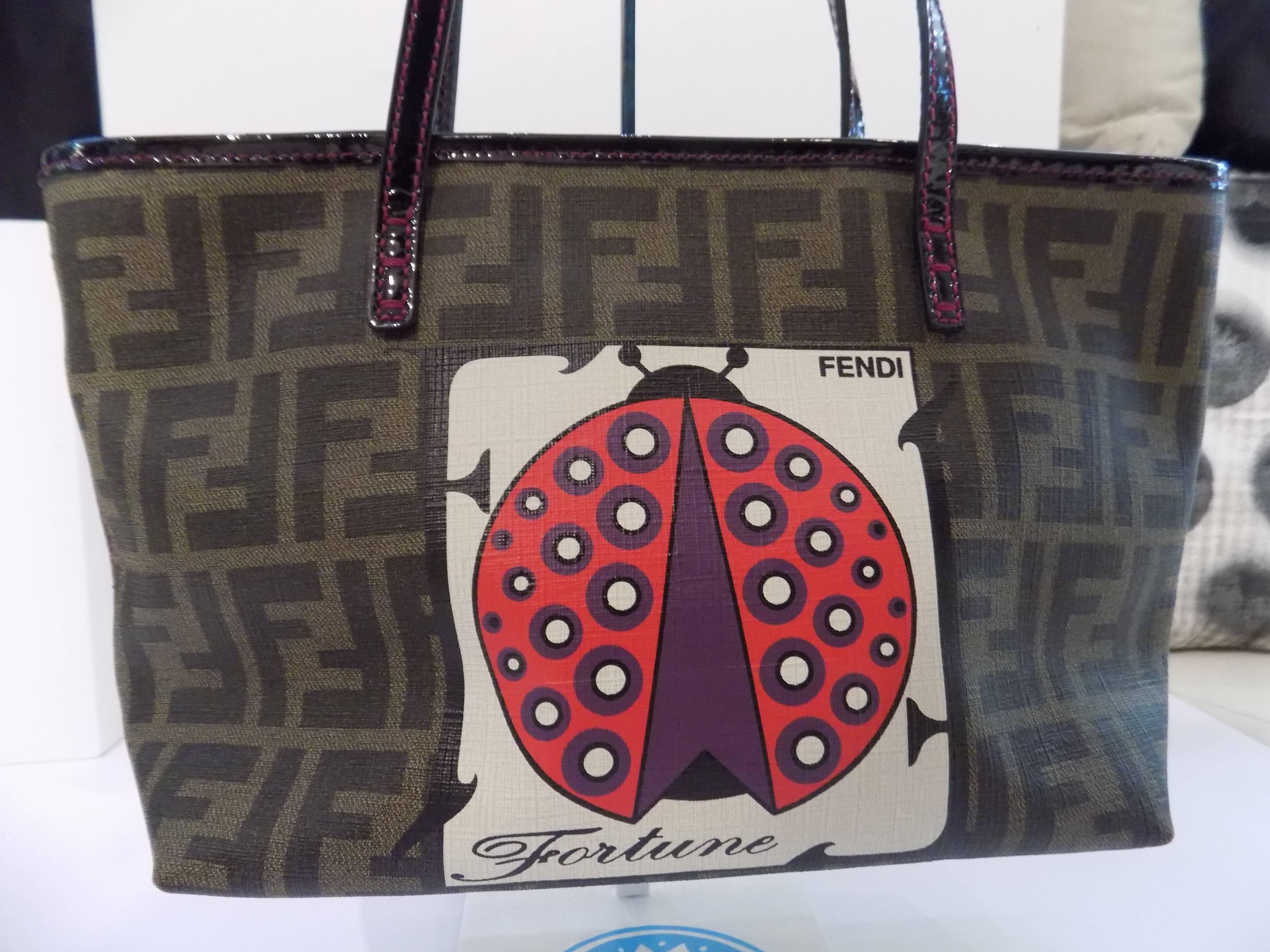 This authentic practical Fendi Zucca Print Canvas Spalmati Lady Bug Tote Bag makes a perfect everyday carryall. It features durable Fendi Zucca printed canvas with patent leather trim and large screen print of a lady bug on the front. This bag has a