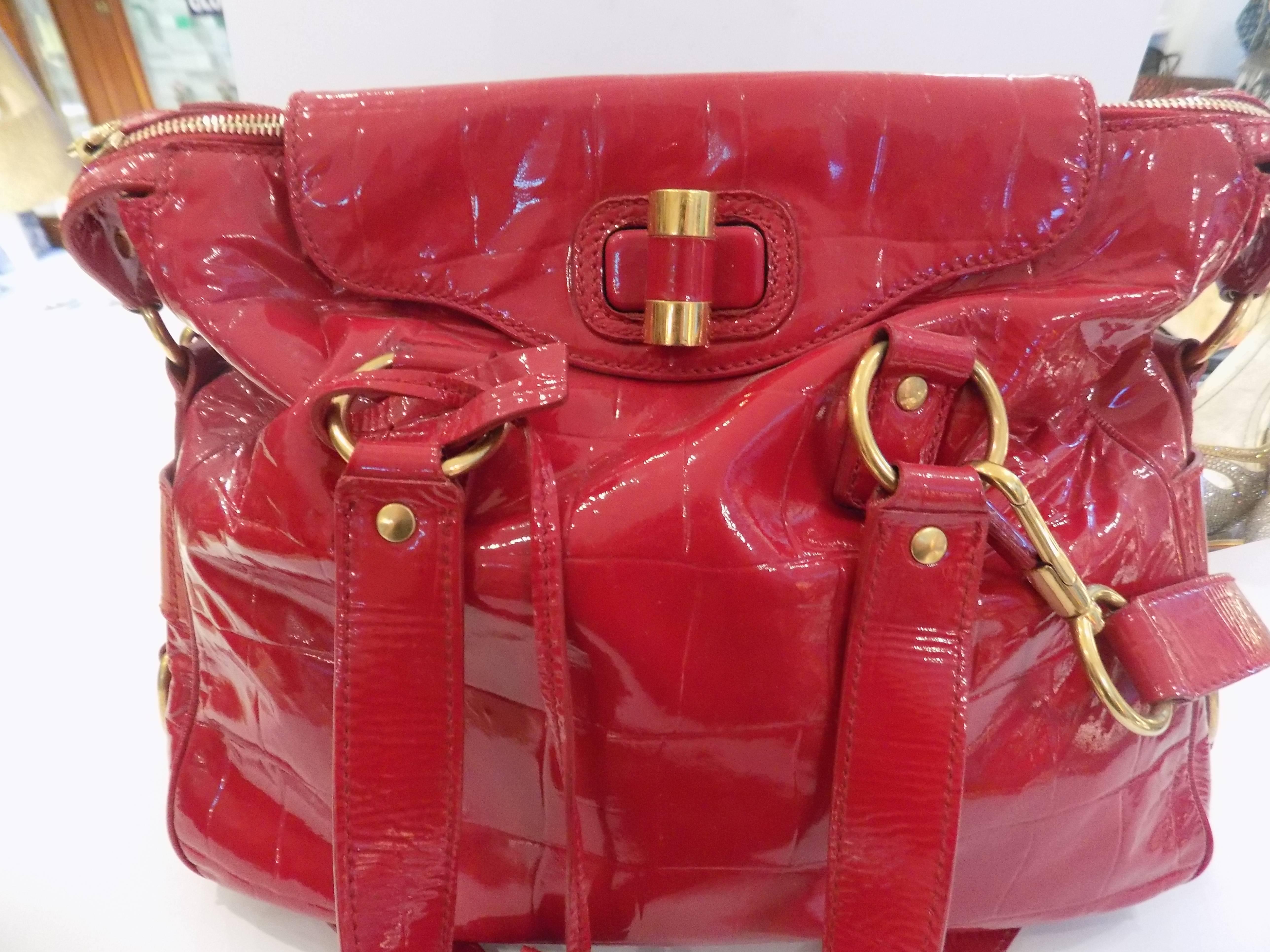 Yves Saint Laurent Red Varnish Leather Bag
The Yves Saint Laurent Slate  Leather Medium Rive Gauche Bag is as chic as they come. It features beautiful slate red varnish leather, goldtone hardware detailing, two top handles and a long strap. The top