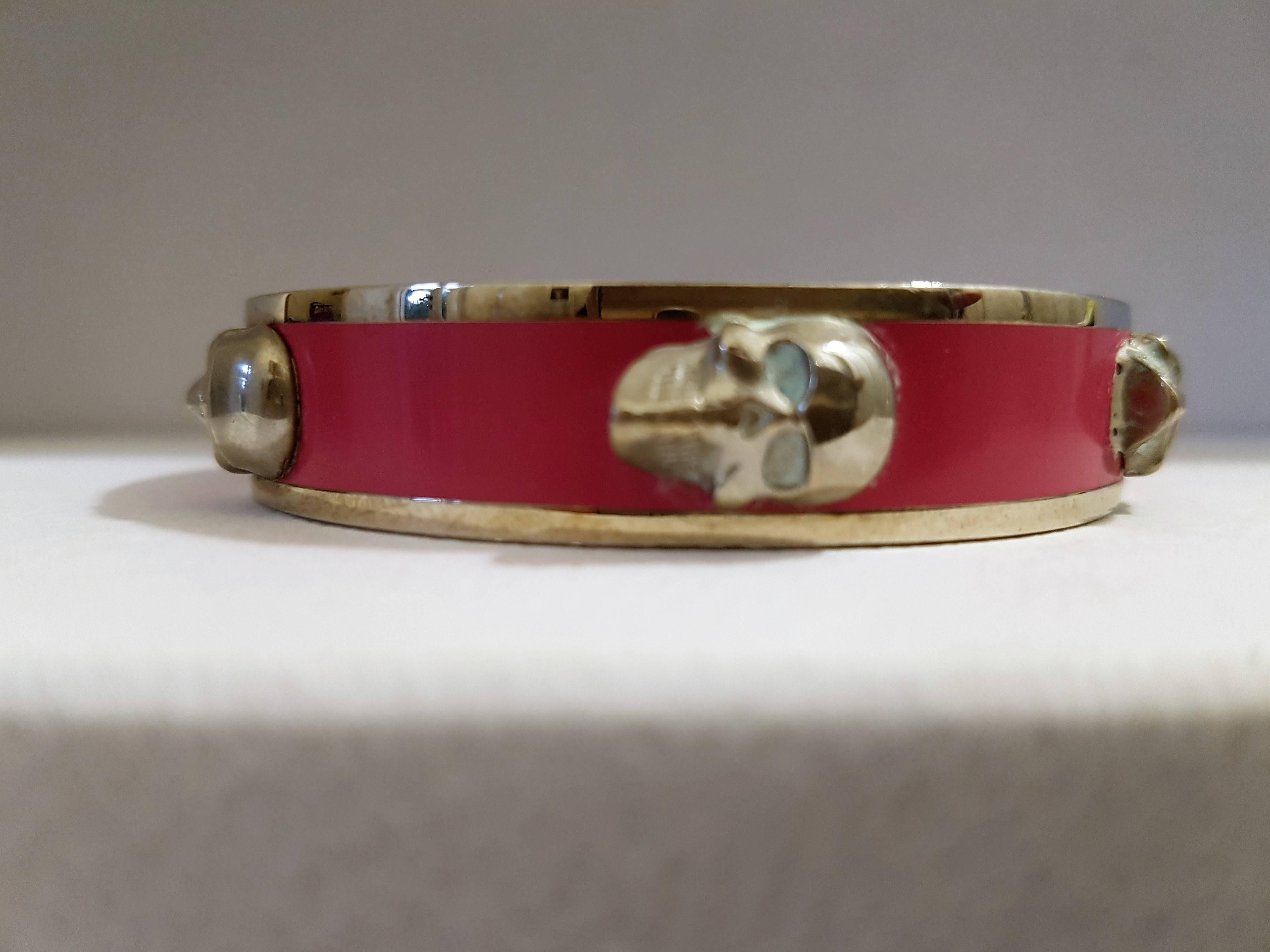 Silver tone and fucsia brass detailed skull Bracelet by Alexander McQueen with embossed logo.