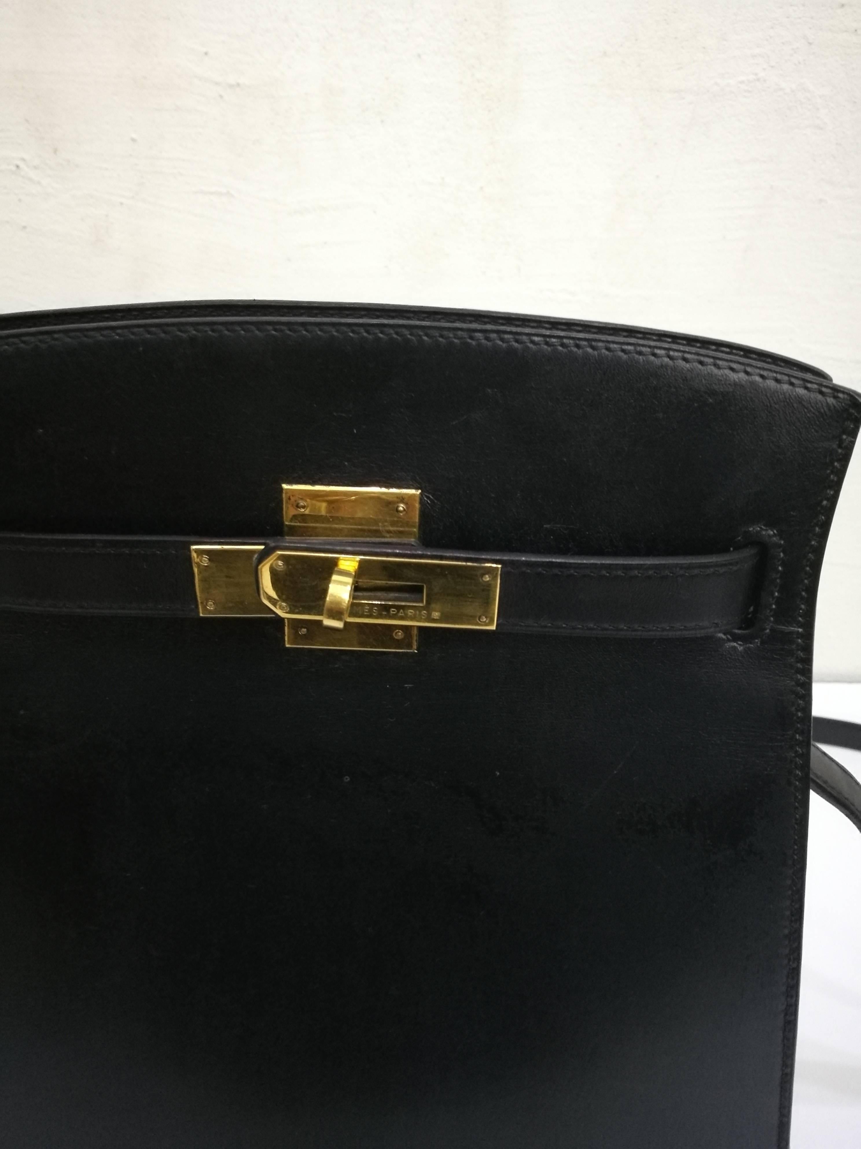 Black leather 'Kelly' sport bag from Hermès Vintage featuring an adjustable shoulder strap, a gold plated hardware, a front clasp fastening, internal embossed logo, a pebbled leather texture and a pouch pocket. Please note that vintage items are