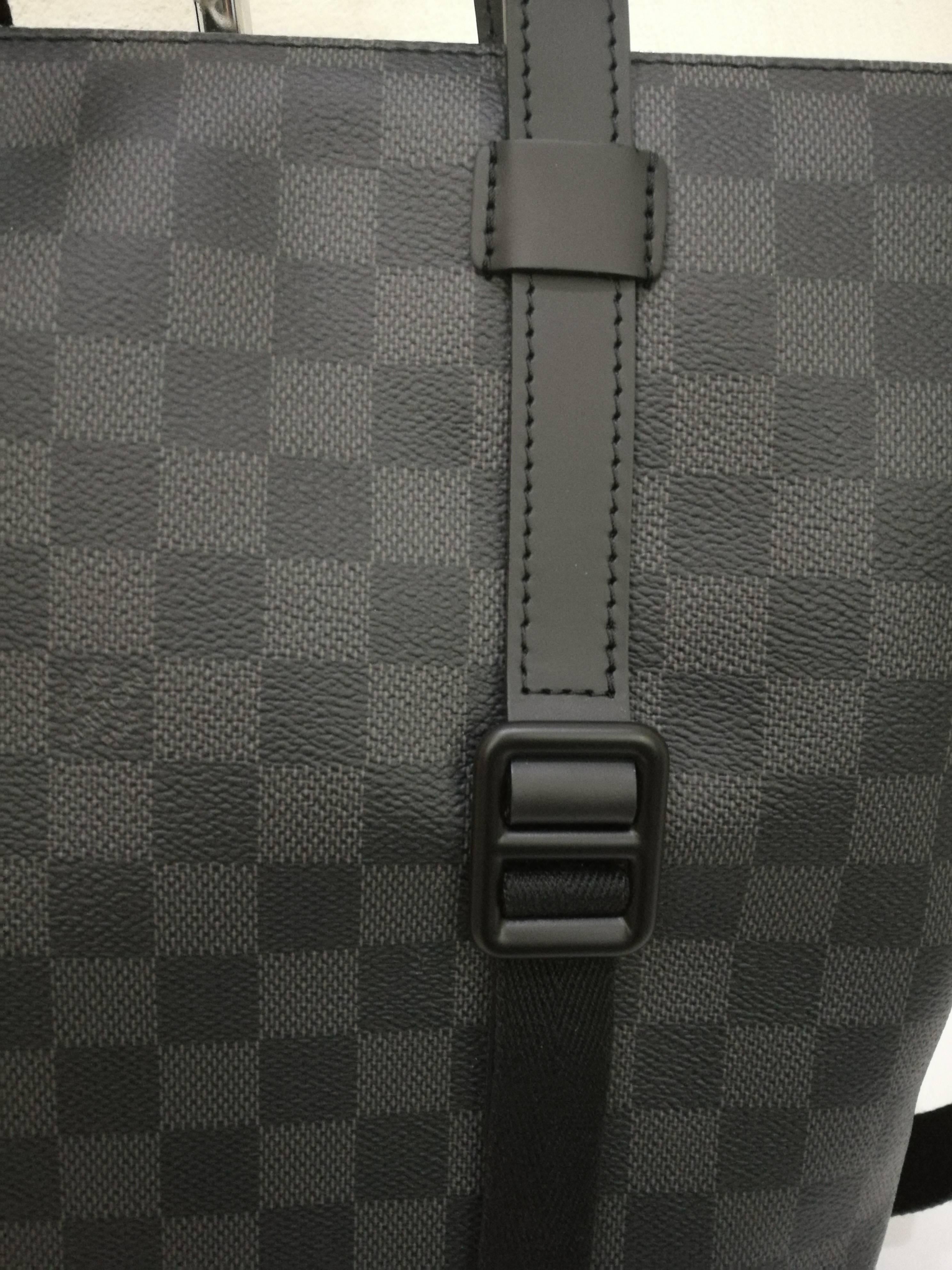 LOUIS VUITTON Damier Graphite Tadao 
This stylish cross-body bag is crafted of Louis Vuitton signature damier checked toile canvas. The bag features a nylon adjustable cross-body strap with silver hardware and rolled leather top handles with silver