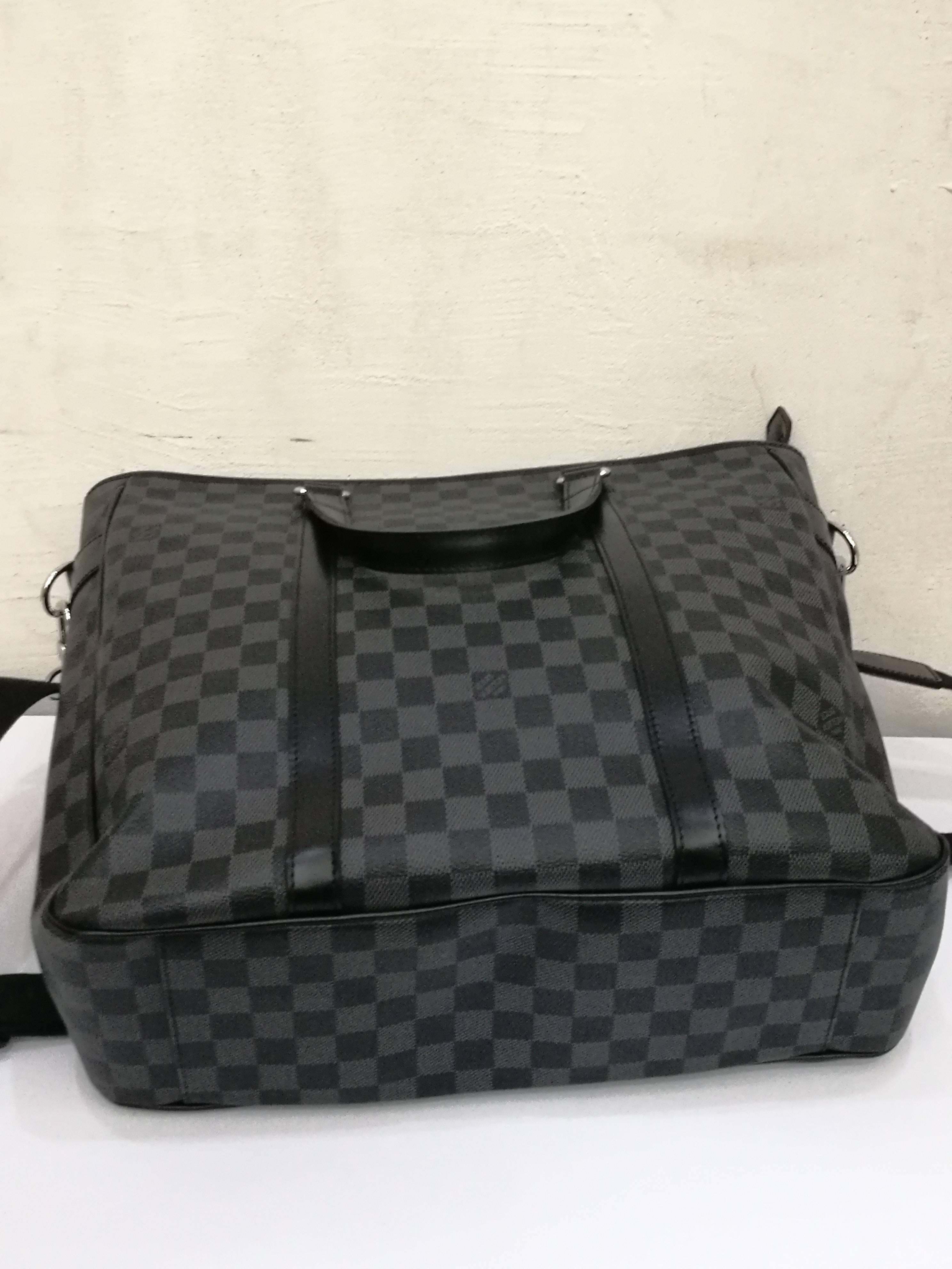 LOUIS VUITTON Damier Graphite Tadao
This stylish cross-body bag is crafted of Louis Vuitton signature damier checked toile canvas. The bag features a nylon adjustable cross-body strap with silver hardware and rolled leather top handles with silver