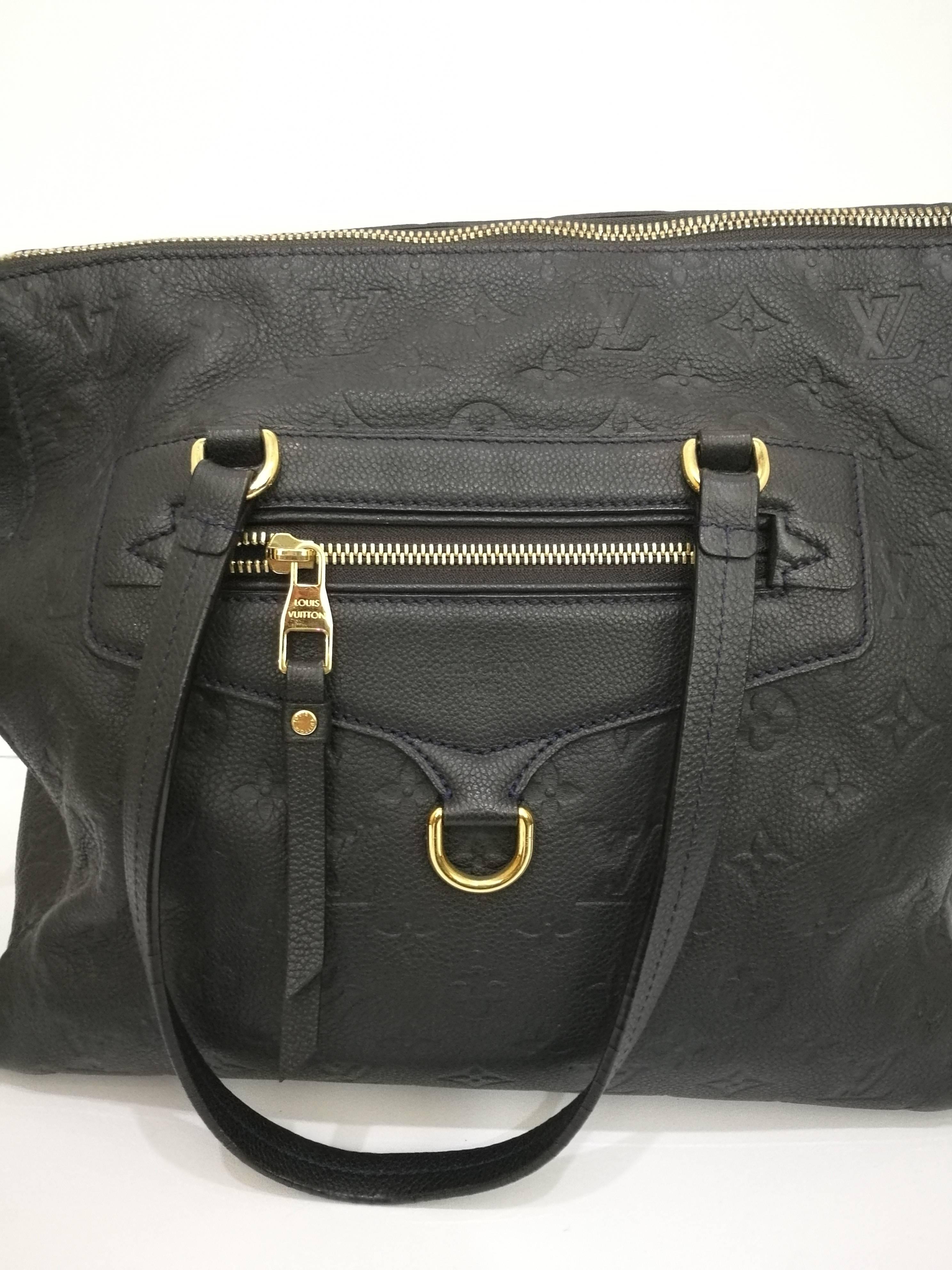 LOUIS VUITTON Monogram Empreinte Lumineuse GM 
This stylish tote is crafted of Louis Vuitton monogram embossed leather and features tall leather strap top handles  a frontal zipper pocket and extensive shiny brass hardware. The top zipper opens to
