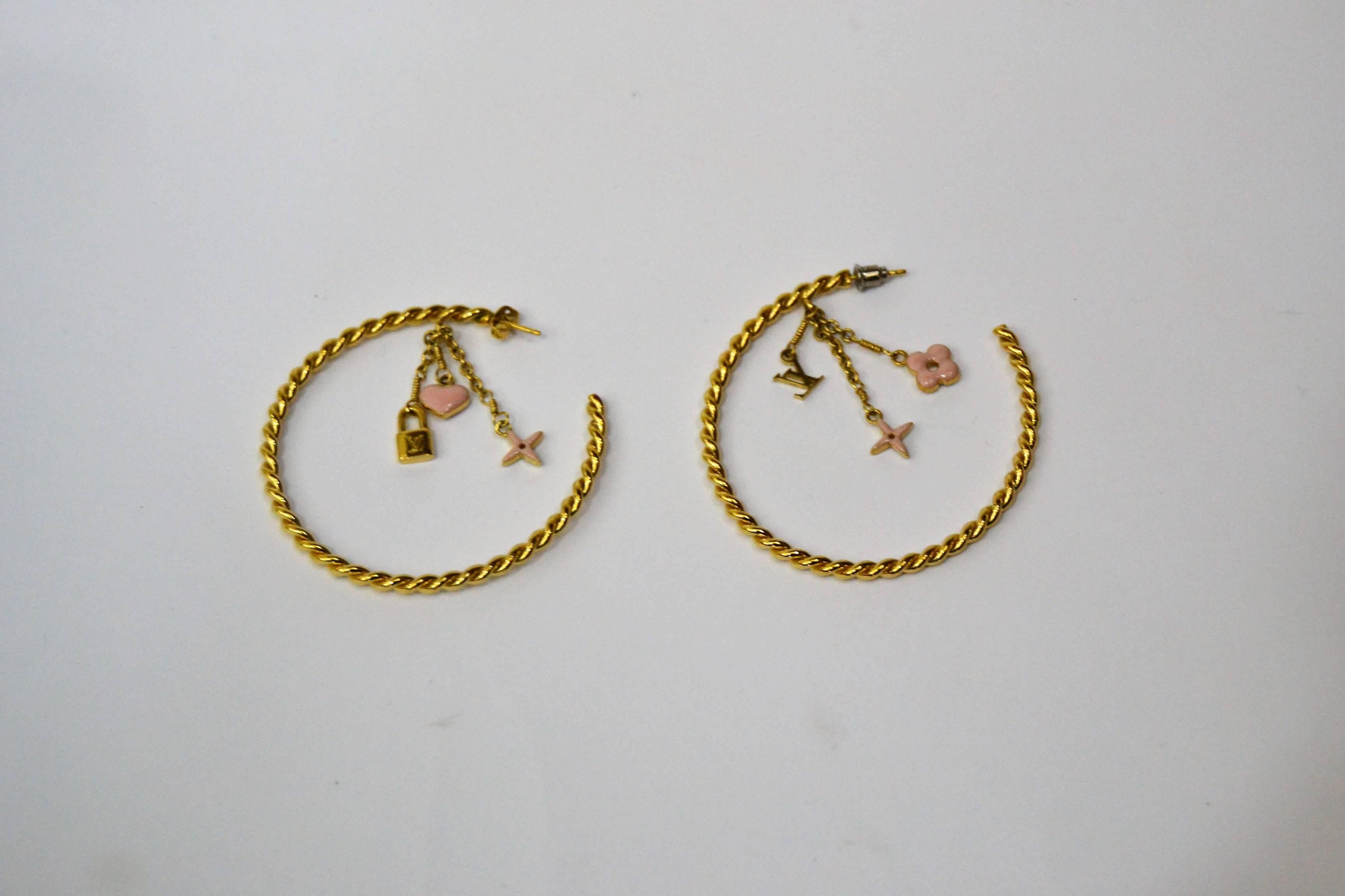 Gold-tone Louis Vuitton 'Sweet Monogram' hoop earrings with pink enamel charms and clutch backings. Includes jewelry pouch.
Metal Type: Gold-Toned Metal
Metal Finish: High Polish
Non-Gem Materials: Enamel
Measurements: Drop 2