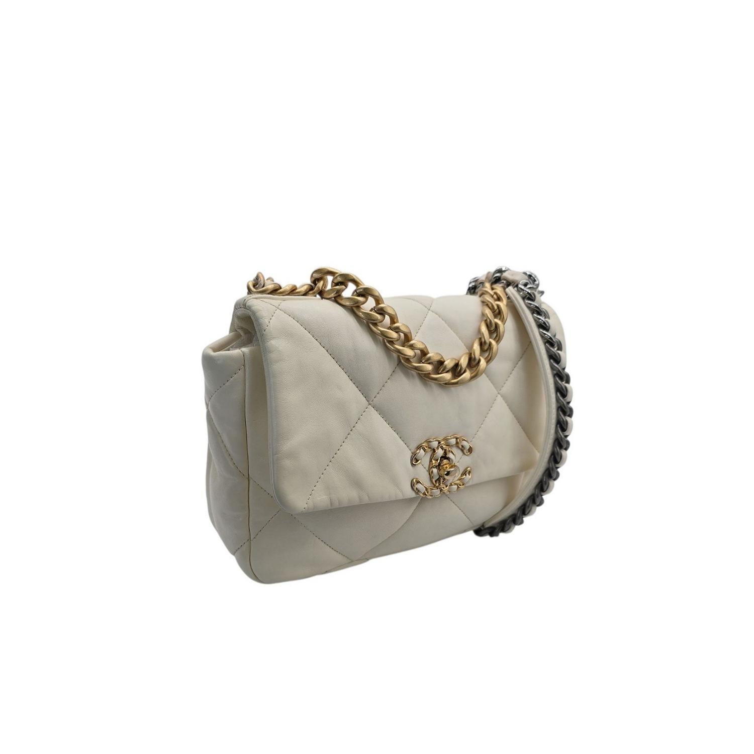 Ce sac à bandoulière doux comme de l'eau de roche est réalisé en cuir d'agneau matelassé surdimensionné de couleur blanche. Le sac est doté d'un fermoir CC à chaîne vieillie sur le rabat, d'une pochette magnétique à l'arrière et d'une bandoulière à