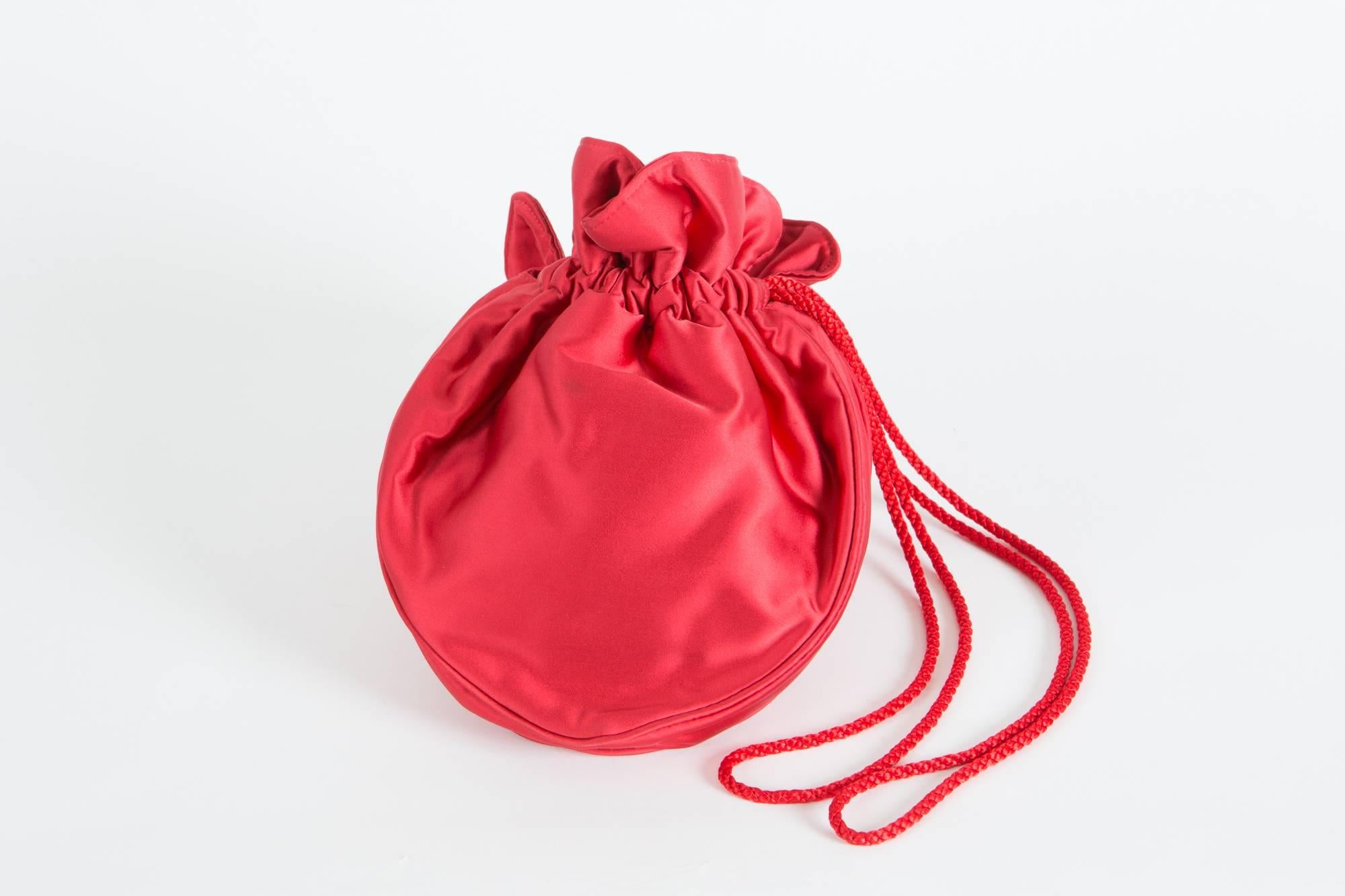 Emblematic Saint Laurent red satin heart bag featuring a heart shape,   a braided shoulder strap, an inside silk lining with an inside zipped pocket. 
Maxi length: 10,2in  (26cm) 
 Maxi width: 9in. (23cm) 
 Maxi side depth: 1,3in. (3cm)
In