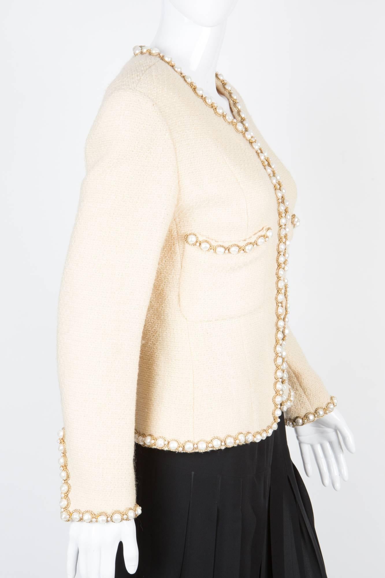 Rare Chanel ivory tweed jacket featuring wool boucle fabric, false-pearls & gold tone embellishments finishing a silk logo lining, and a 24kt gilded gold hardware chain in the bottom lining. 
In excellent vintage condition. Made in France.
We