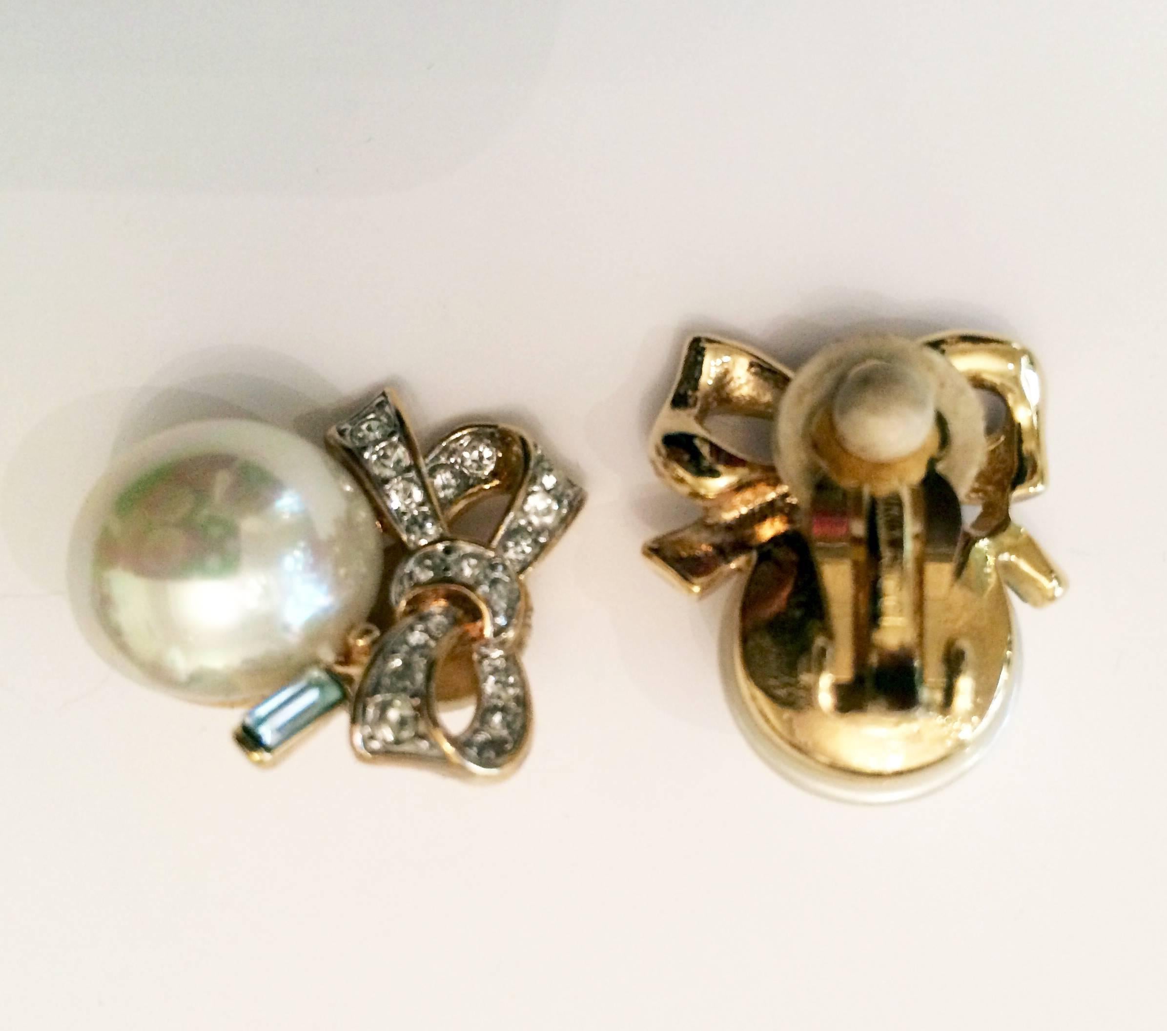 Iconic 1990s Nina Ricci earrings featuring white faux pearl balls and crystal stone decorated tied on the back side has the logo 