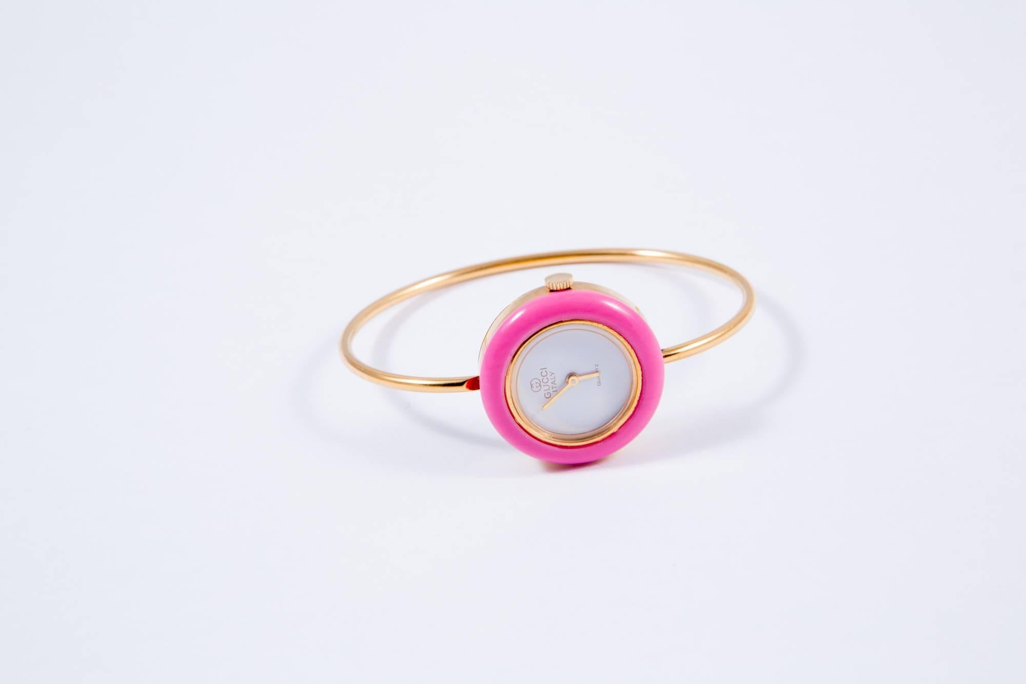 1970s Gucci gold plated bangle watch featuring 10 multicolor interchangeable bezels, a clasp fastening opening. Gold bezel is metal, all others are plastic. There are 12 bezels in the set including the red/green strip Gucci logo colors. Delivered in