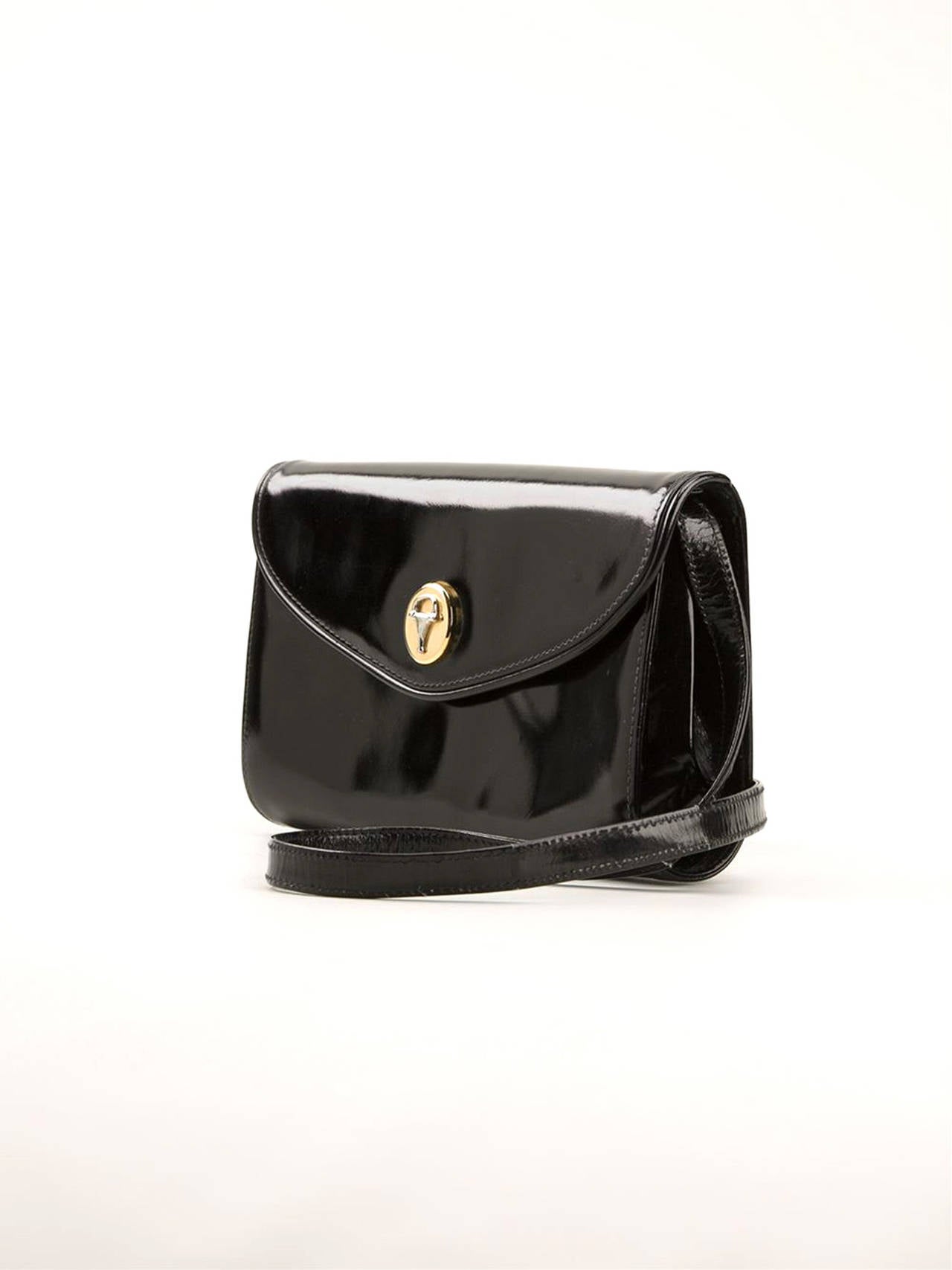 1970s black patent leather clutch from Gucci Vintage featuring a front flap closure, with a gold-tone logo plaque, a detachable shoulder strap ( 48cm) , a magnetic closure and an internal slip pocket. It gets an inside stamp label. 
In excellent