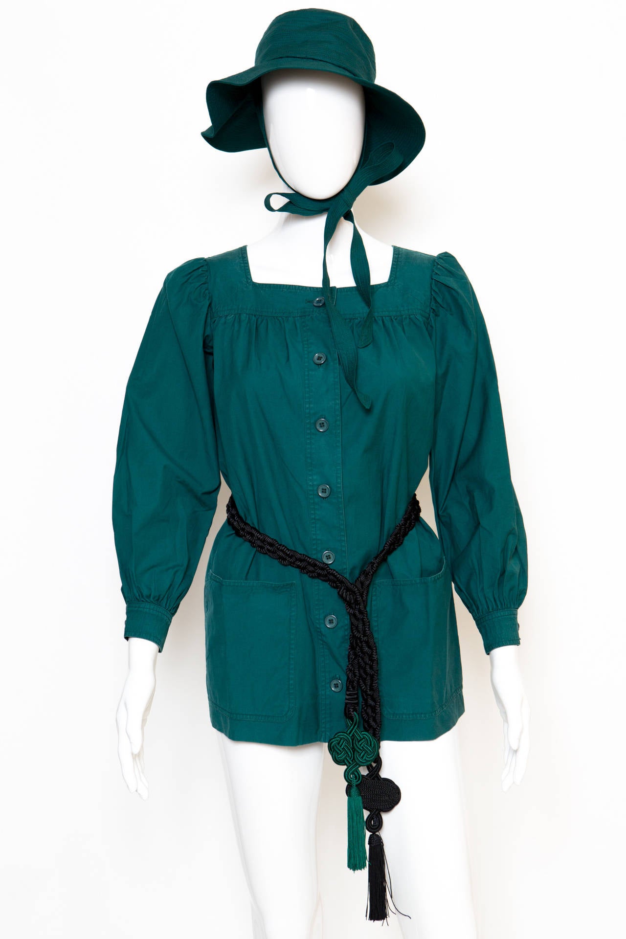 A 1960s Yves Saint Laurent green cotton tunic with a front button opening, buttoned cuffs, front pockets, the top comes with a matching cotton hat ( total circumference : 52cm).
Belt not coming with the 2 pieces set.
Estimated size : 36 fr
In