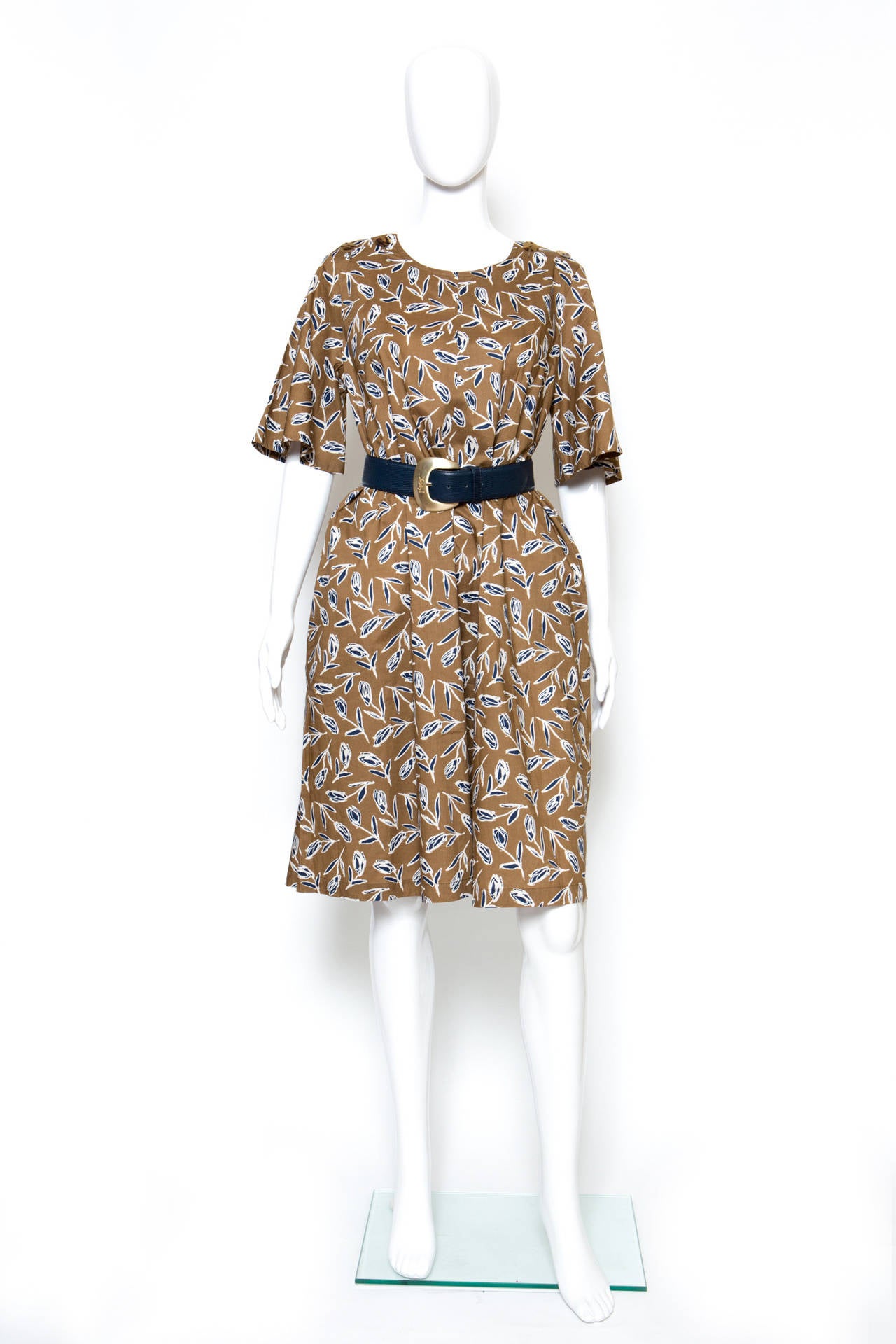 A 1980s Yves Saint Laurent peasant cotton dress in a fantastic tulip print with three quarter length flouncy sleeves, a round neckline with shoulder decorative buttons and side pockets. The dress comes with a leather blue Yves Saint-Laurent belt
