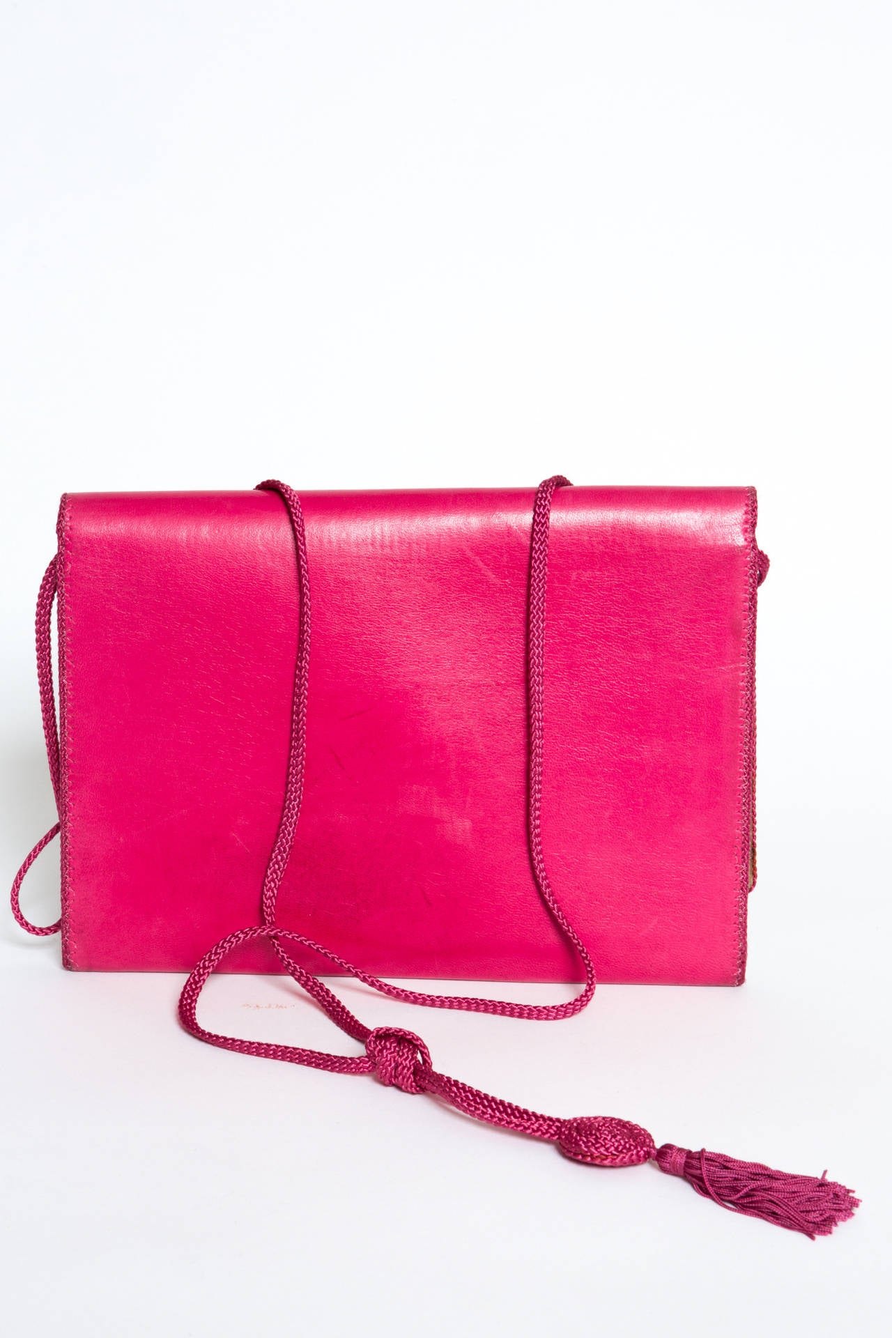 Fabulous, fuschia Saint-Laurent leather shoulder bag, featuring black stone cabochon, a snap closure, a braided piping aroud the bag and a braided long strap (124cm).