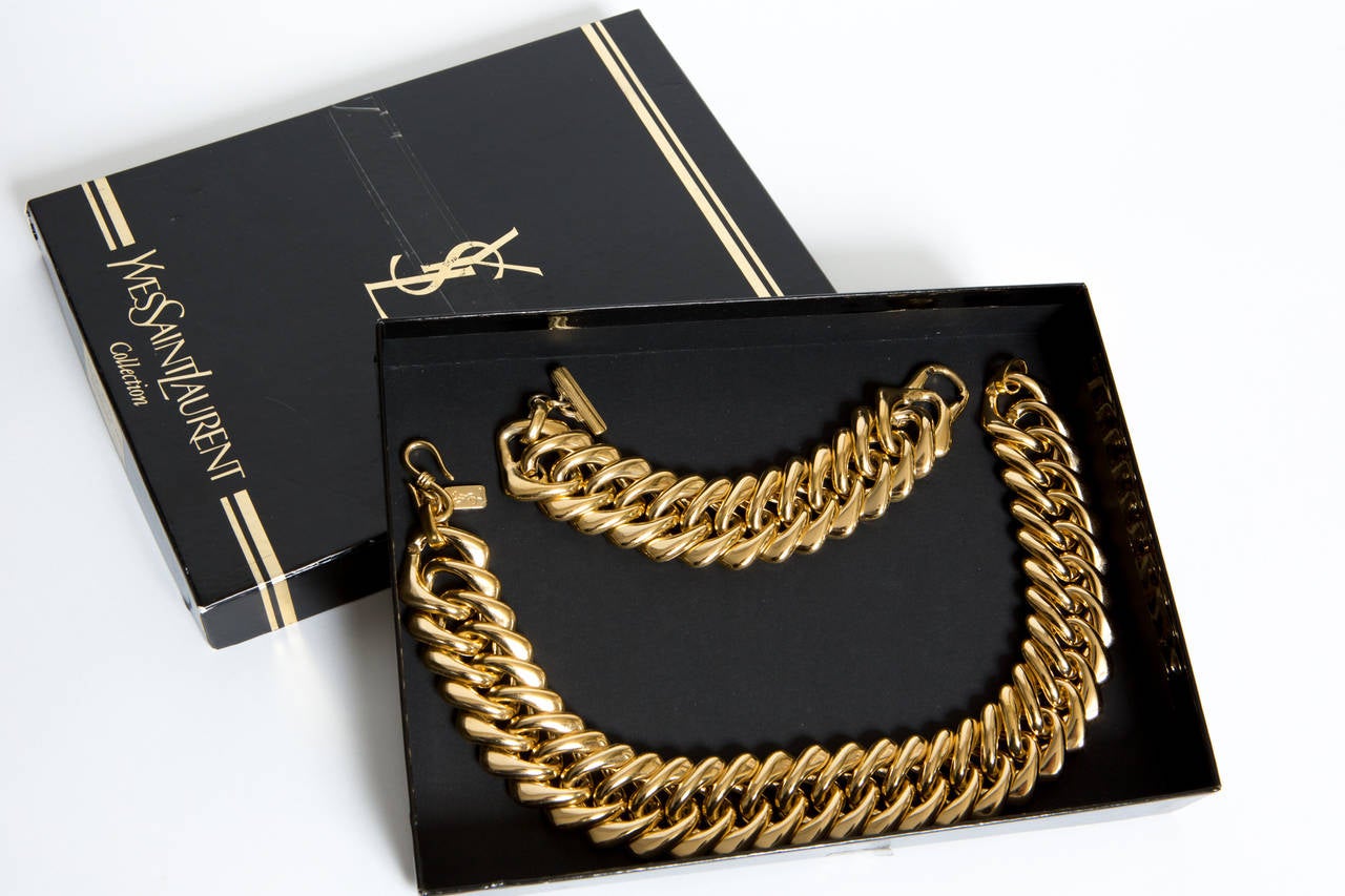 80’s Yves Saint-Laurent  gold-tone signed set with a fabulous choker massive chain necklace and the matching chain bracelet both in excellent condition. Marked on a plaque and delivered in the original box. 
Necklace total length  42cm x 