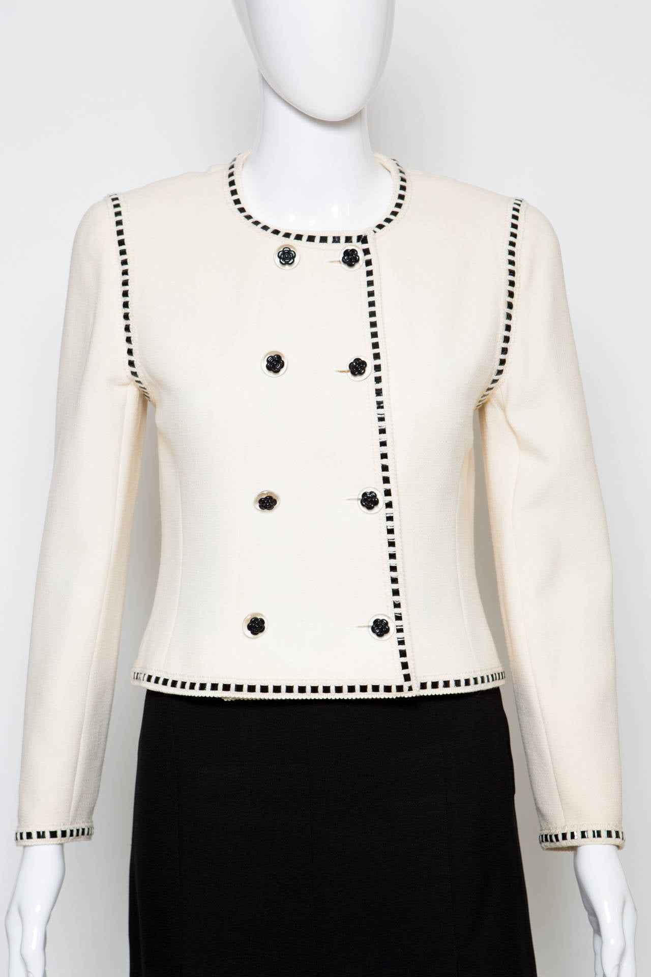 1990s Chanel off-white wool crepe boucle jacket featuring  a black vinyl ribbon at front and at cuffs, transparent and black camellias resin buttons,  a silk logo lining ,  and a 24kt gilded gold hardware chain in the bottom lining.
Estimated size
