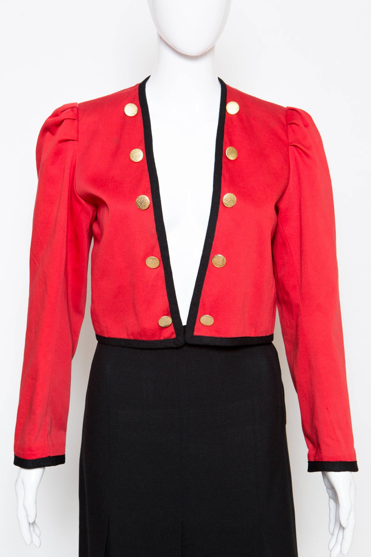 1980s Yves Saint Laurent red cotton bolero,featuring black braid details around neck & cuffs, long sleeves,fully lined,fancy pleated shoulders, gold-tone decorative buttons at front. The bolero gets an edge to edge opening with an inside bottom
