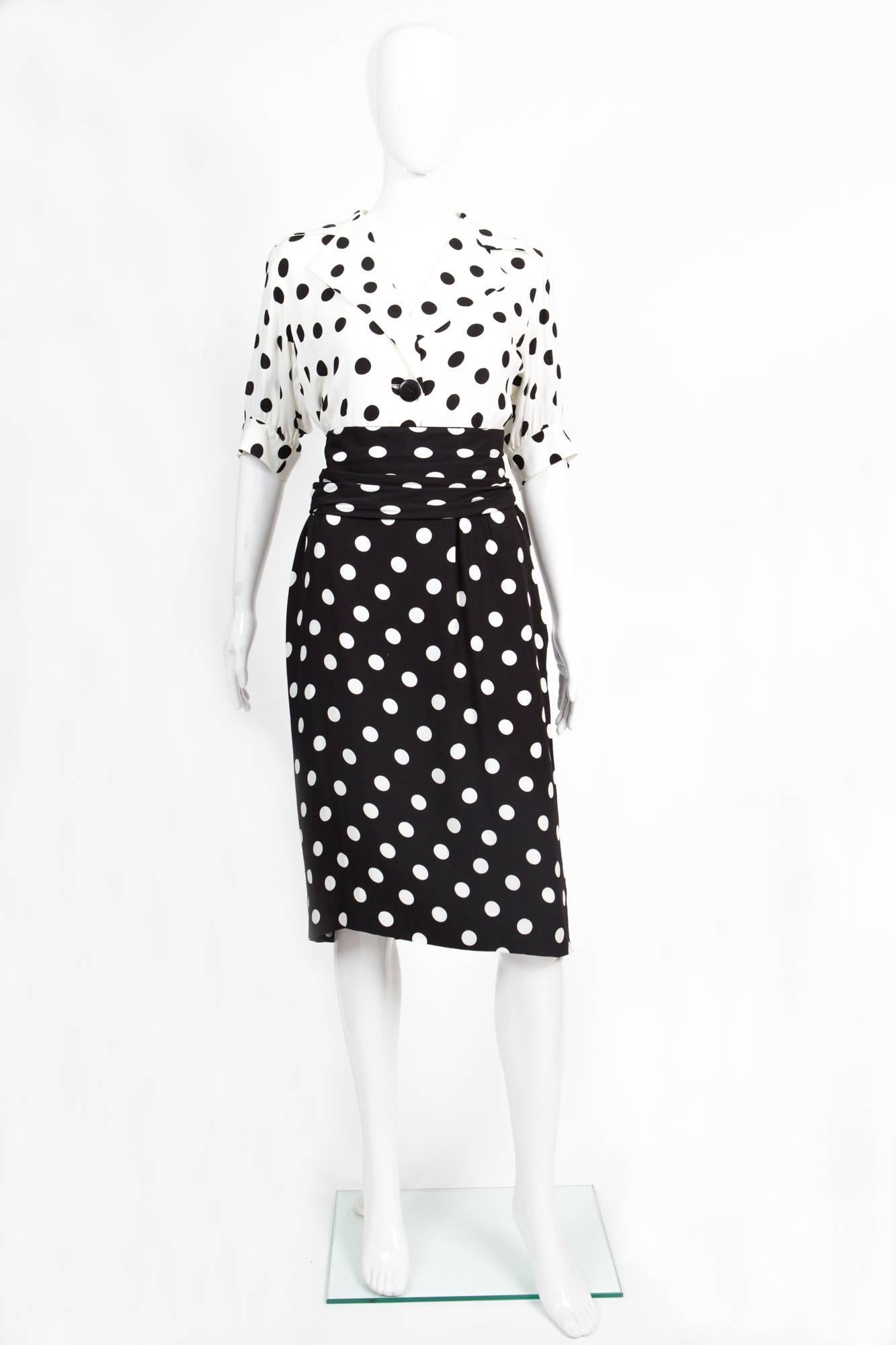 1986s Black and white silk dotted Yves Saint Laurent Vintage dress featuring notched lapels, a button fastening, a ruched waist, a side zip fastening, short sleeves and a knee length and a large  pleated separated belt (10cm width ) closed by hooks.