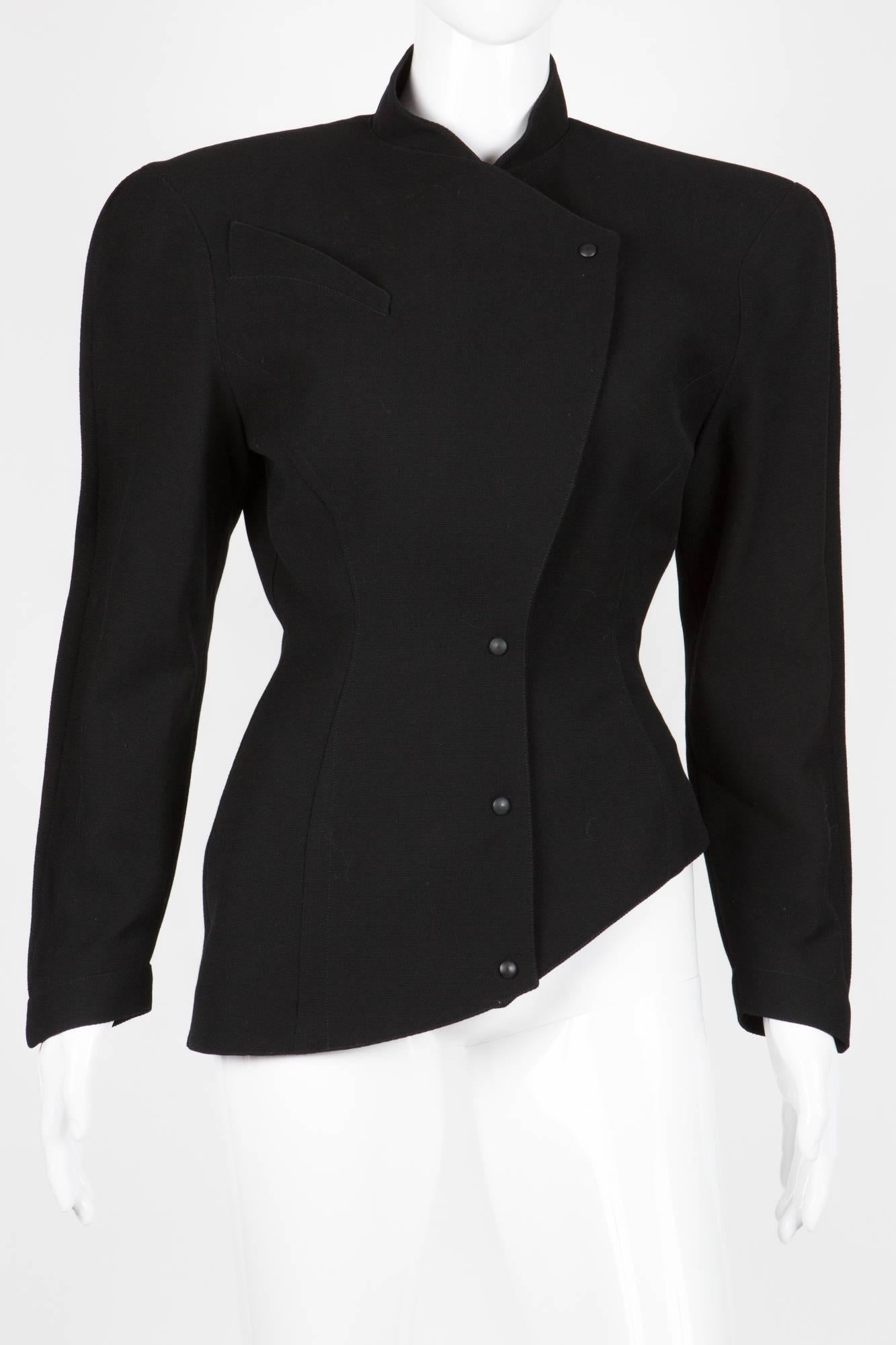 1980s Thierry Mugler black asymmetric crepe wool jacket featuring a center front button opening, Emblematic Mugler volume, this jacket gets large shoulder pads and fitted waistline. This fitted jacket is fully lined. 
In excellent vintage