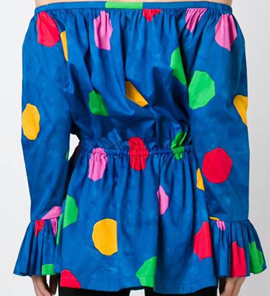 Iconic bright blue cotton dot print off shoulder Saint Laurent blouse featuring a boat neck, a multicoloured dot print on a blue tie & dye ground, an elasticated waistband, long sleeves and flared cuffs.
In excellent vintage condition. Made in