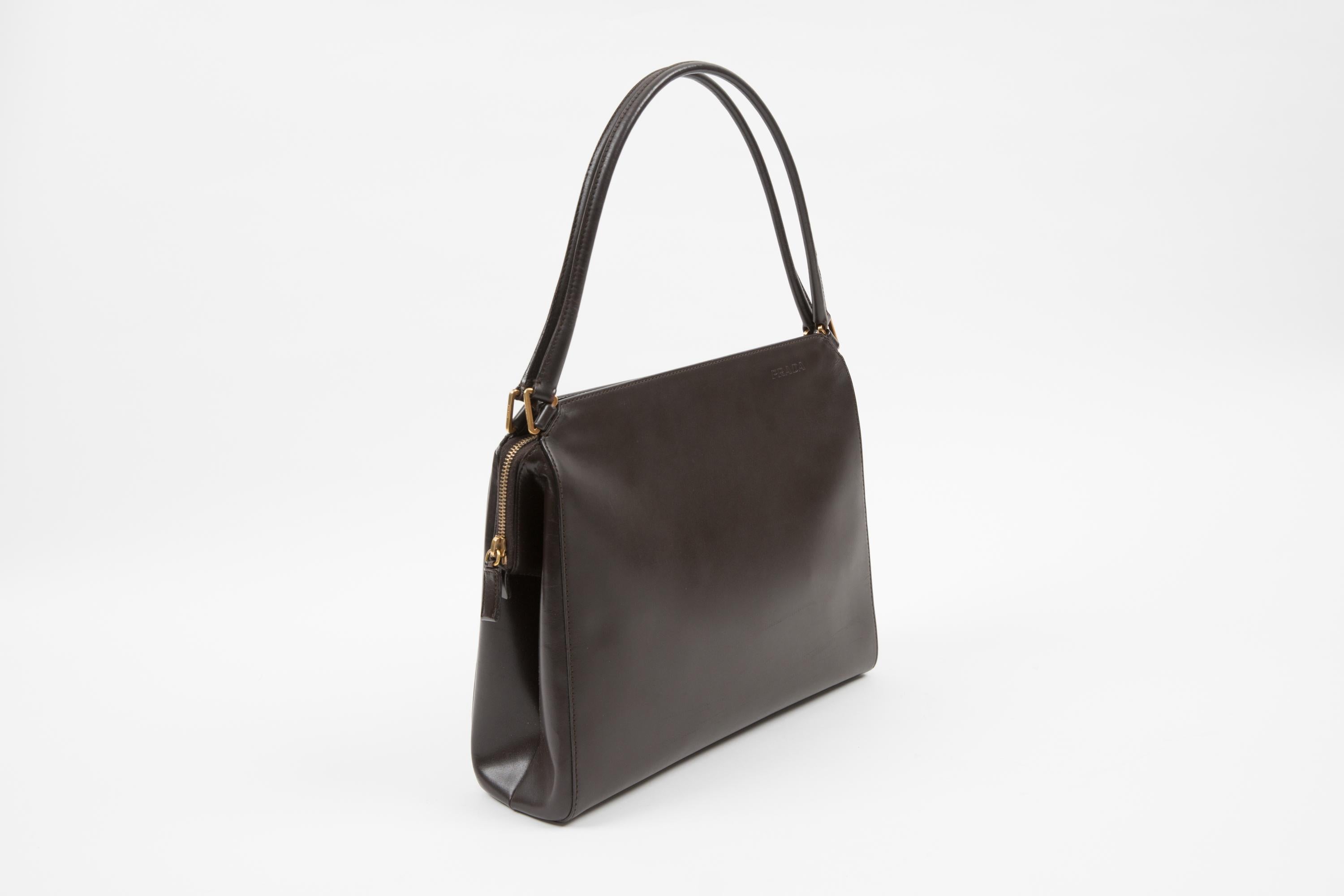 Sac à main en cuir marron de Prada présentant une quincaillerie dorée, une fermeture zippée sur le dessus, une doublure intérieure à logo, une poche intérieure zippée. 100% cuir.
Vers les années 2000.  100% cuir
En bon état vintage. Fait en