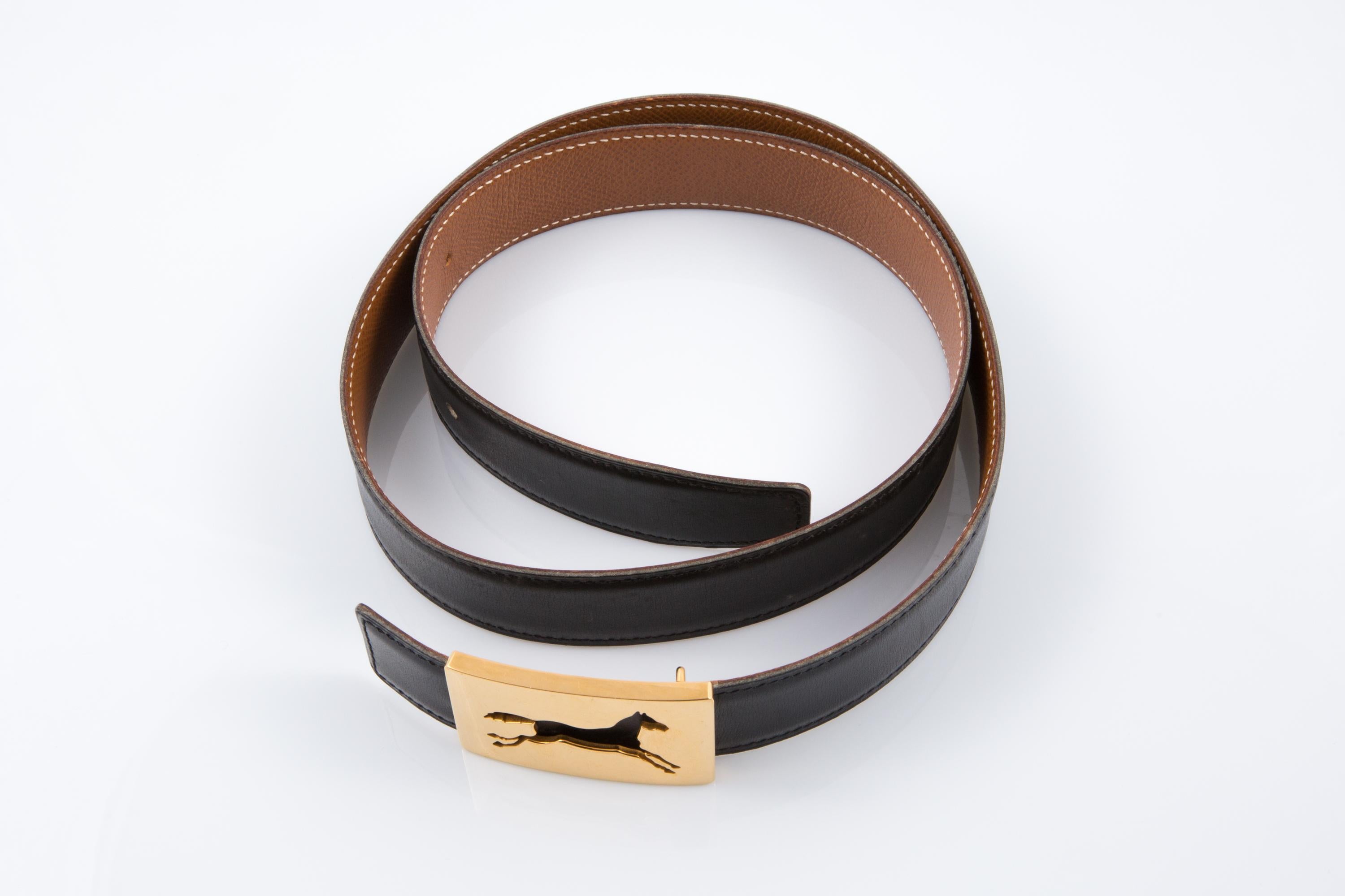 Hermes Schwarzes Pferd Schnalle Box Ledergürtel mit innen Kamelleder, ein Pferd ausgeschnitten vergoldete Schnalle, ein entsteintes X in einem runden. 
CIRCA 1994 Hergestellt in Frankreich
Gürtel Größe fr:85 
CIRCA 1994 (X in einer Runde)
Länge des