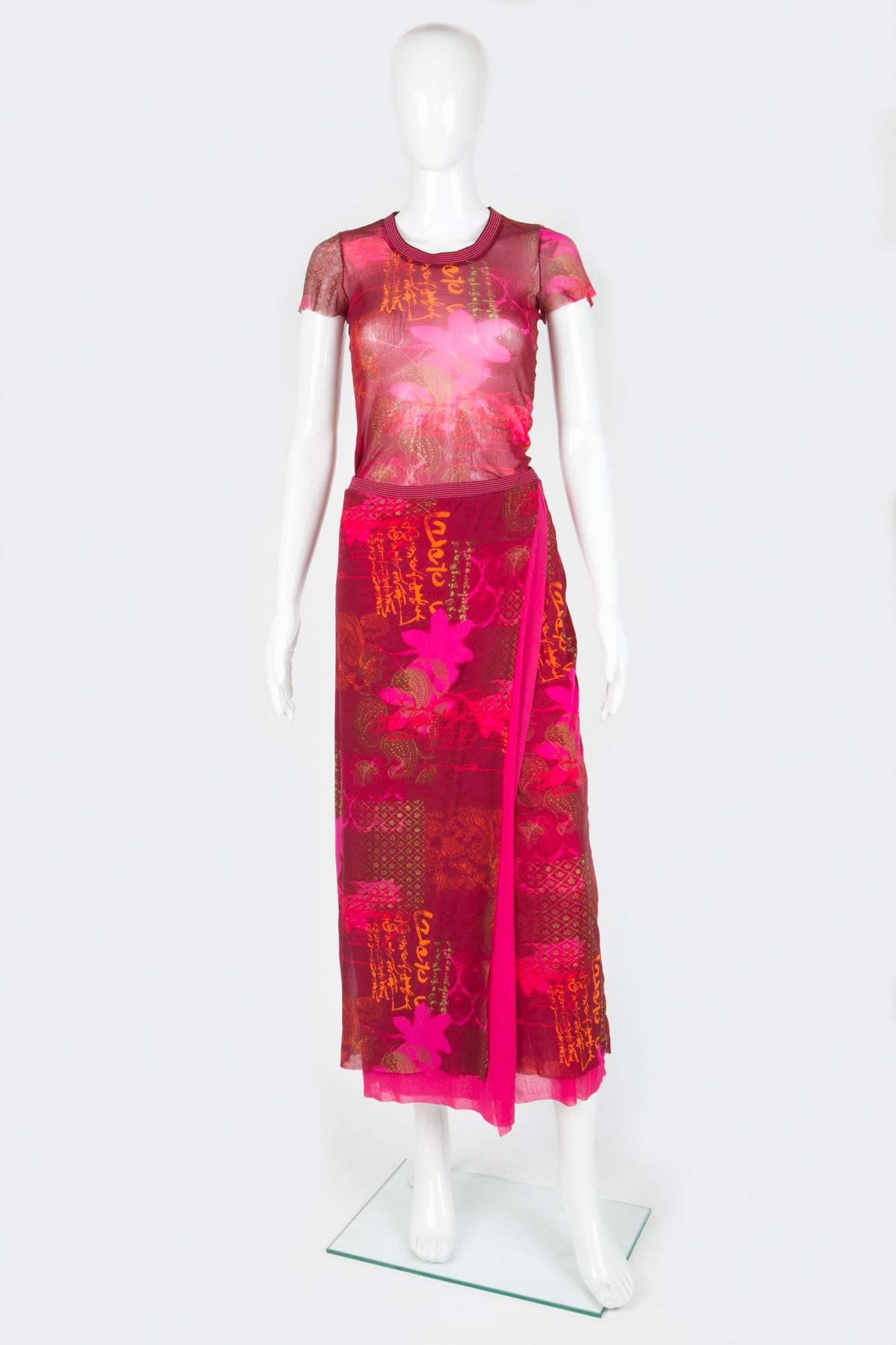 Red sheer Kenzo suit featuring a multi ethnic print all over, a top and a fixed wrapped skirt. Skirt is fully lined in bright pink & gets a knitted  stripy waistband, The top is unlined, gets raw edges & a knitted stripy band at the