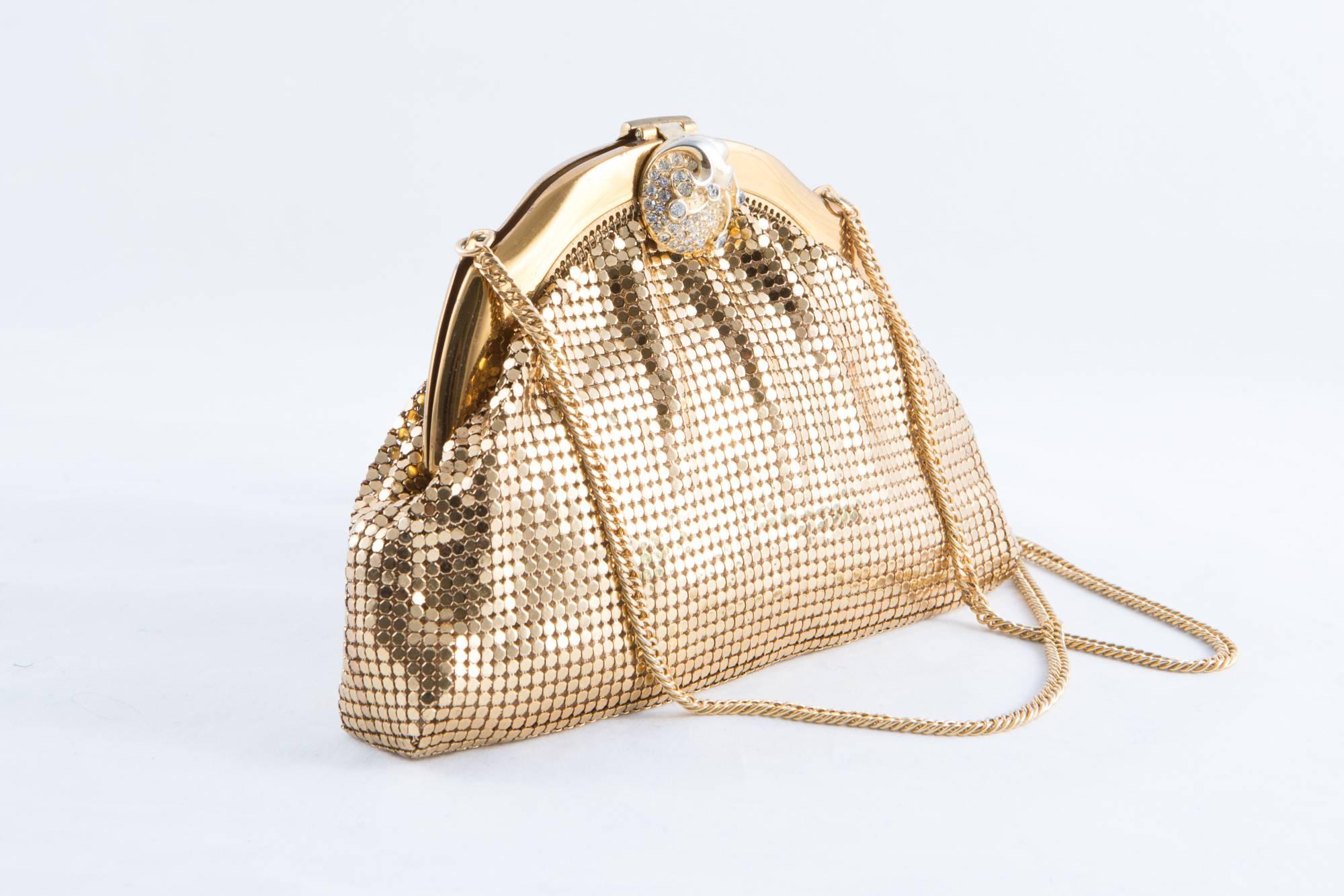 Gold mesh Whiting & Davis evening clutch featuring a gold and strass top clasp closure, an inside peach color silk lining and gold chain handle. (Length:32,2 in. (82cm)).
Bottom bag 7in. (18cm) X Heigth: 5,1in. (13cm) 
In excellent vintage