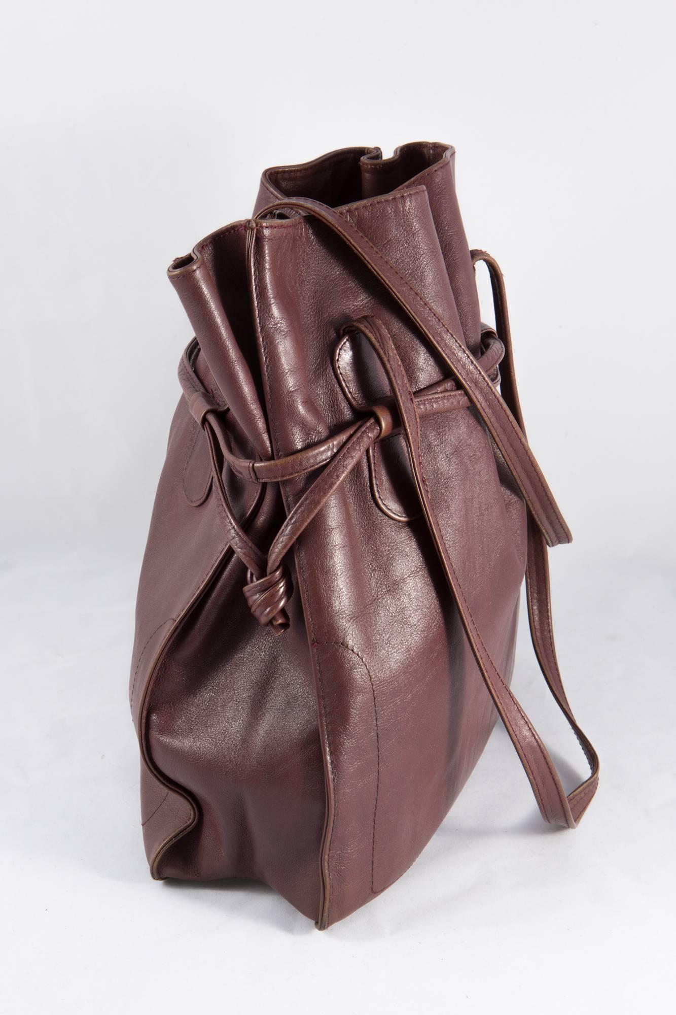 Bordeaux large Pierre Cardin leather bucket bag featuring two top shoulder handles, an around bag drawstring, an outside silver tone logo, an inside gold tone stamp 