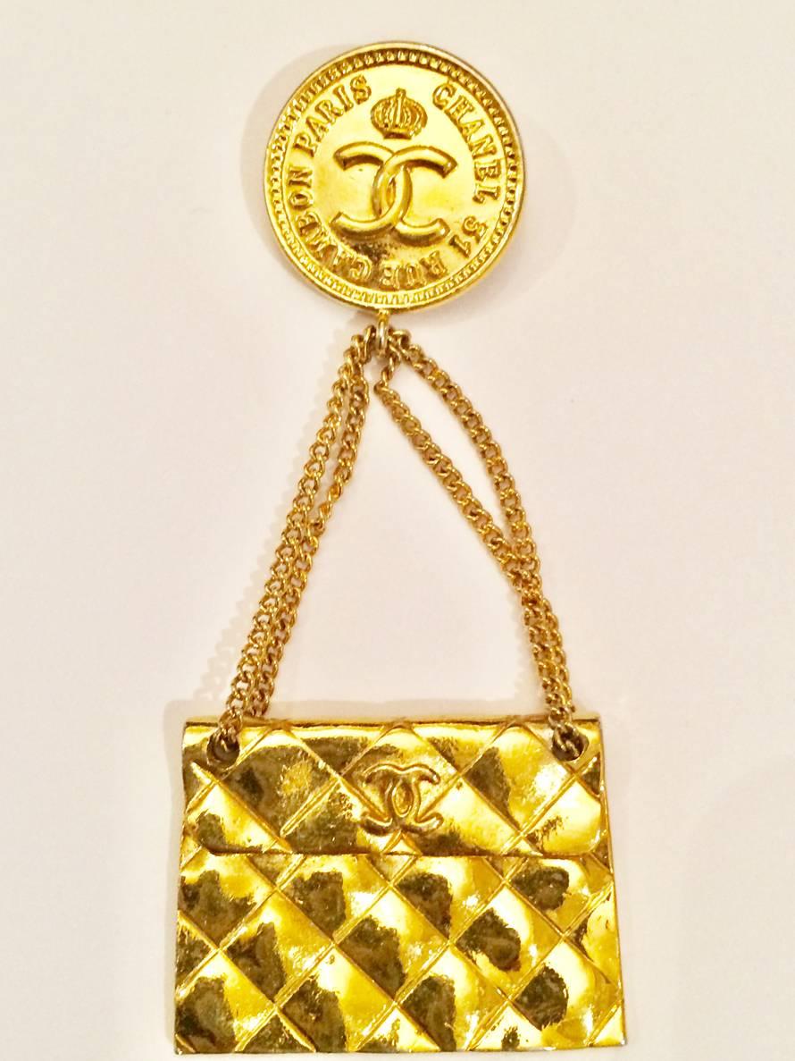 2005s Chanel gold tone handbag brooch featuring a front logo plaque, an embossed logo to the rear, a bar pin fastening and a quilted effect.  
Chanel signature plaque on the reverse . 
Length: 2,7in (7cm) X 1,5in. (4cm) 
In excellent vintage