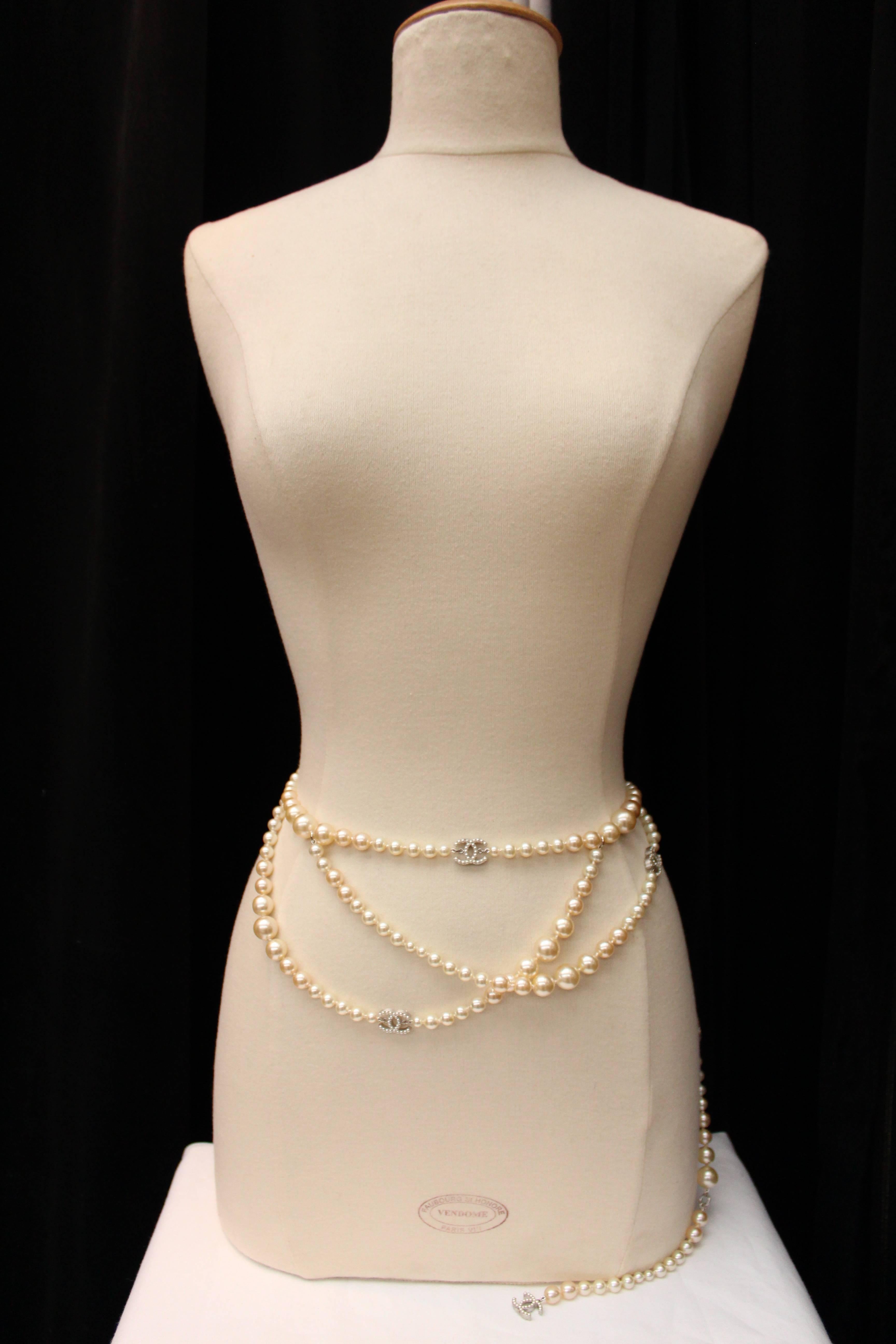 CHANEL (Made in France) Belt that can be worn as a necklace comprising of several rows of faux pearls of different sizes and different shades of mother-of pearls alternated with five gilt metal CC logos paved with mother-of-pearl very small