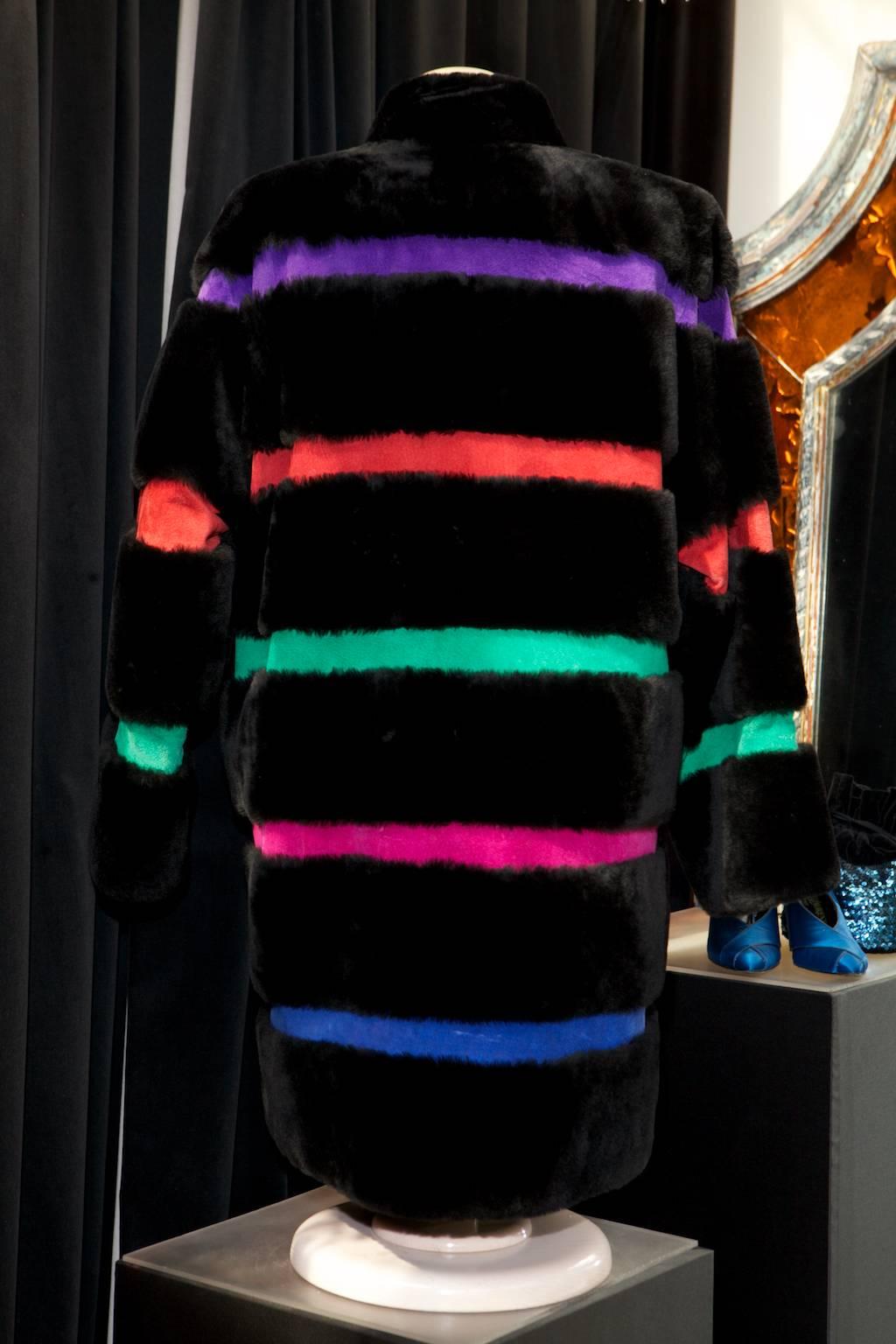 YVES SAINT LAURENT FOURRURE mid length coat with long sleeves made of black dyed sheep fur alternating thin strips of suede in purple, red, green, pink and blue colors

The coat fastens in the front with a button-five black resin buttonhole