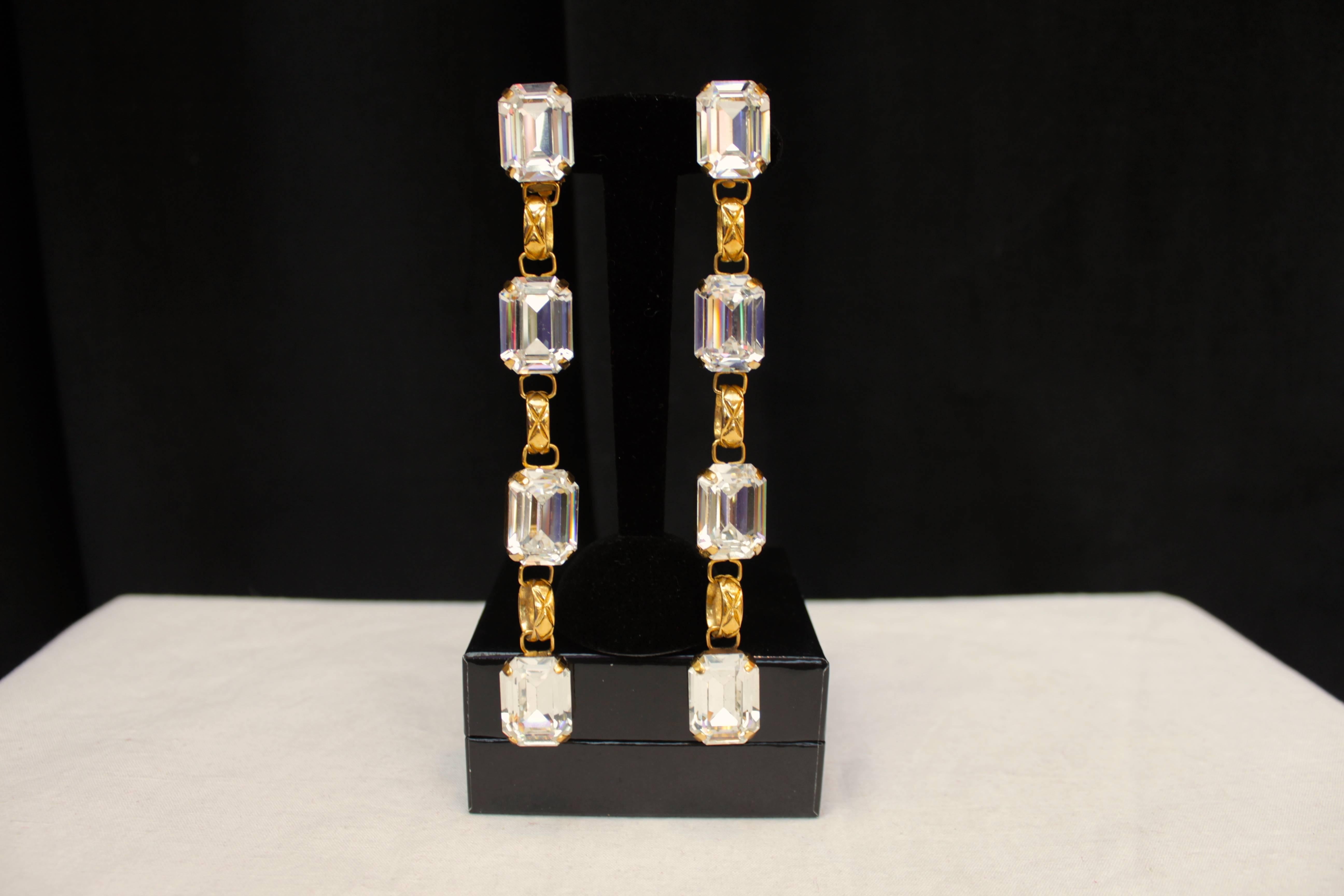 CHANEL (Made in France) Pair of pendant clip on earrings featuring white rectangular crystals with an emerald cut, alternating with quilted gilt metal chain links.

Collection 2 5 from the early 1990s.

Very good condition.

Measurements: