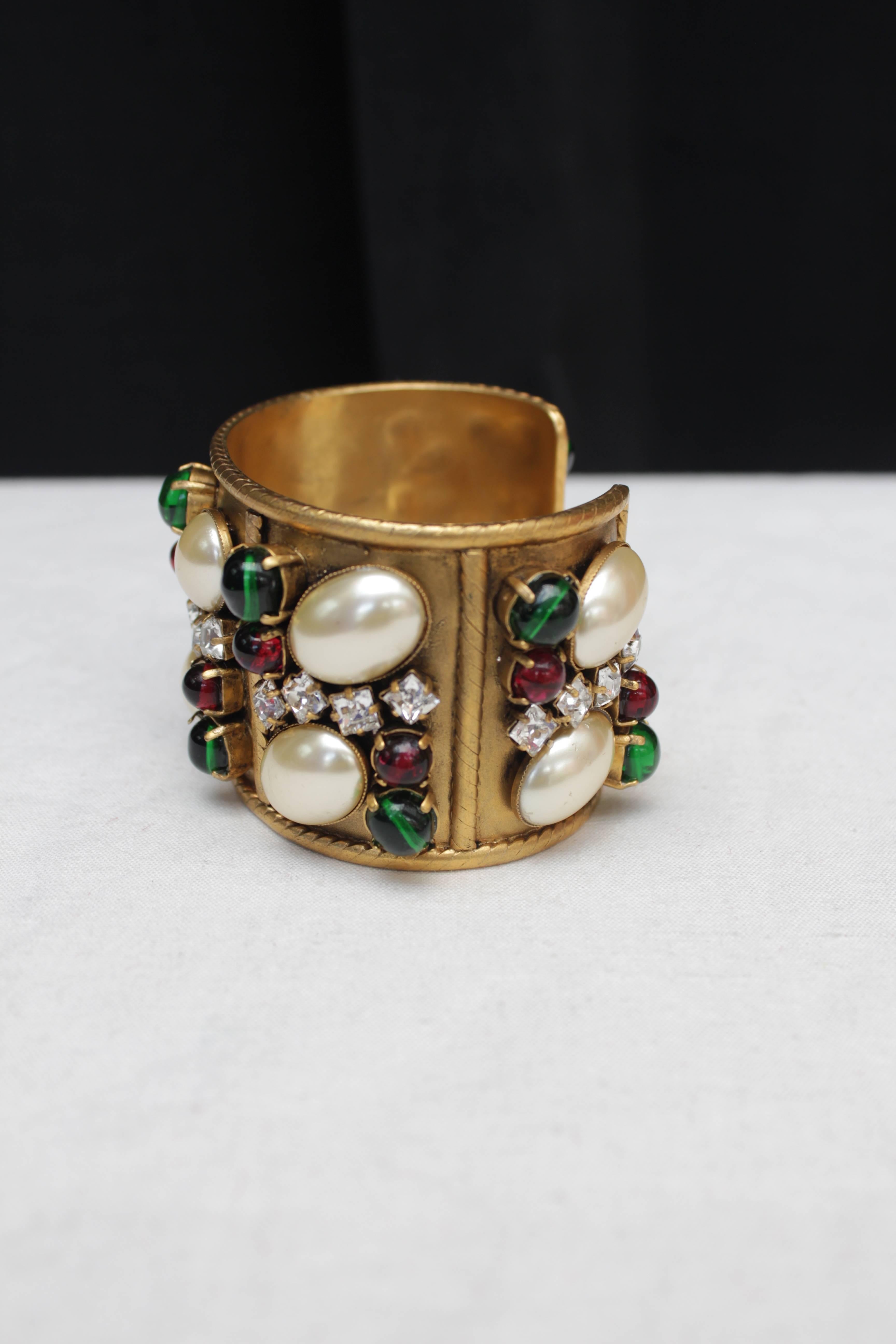 CHANEL (Made in France) Beautiful cuff in patinated gilt metal paved with emerald and ruby colored glass cabochons, faux-pearl cabochons and square white rhinestones.

Collection 2 5 from the early 1990s.

Very good condition (one cabochon