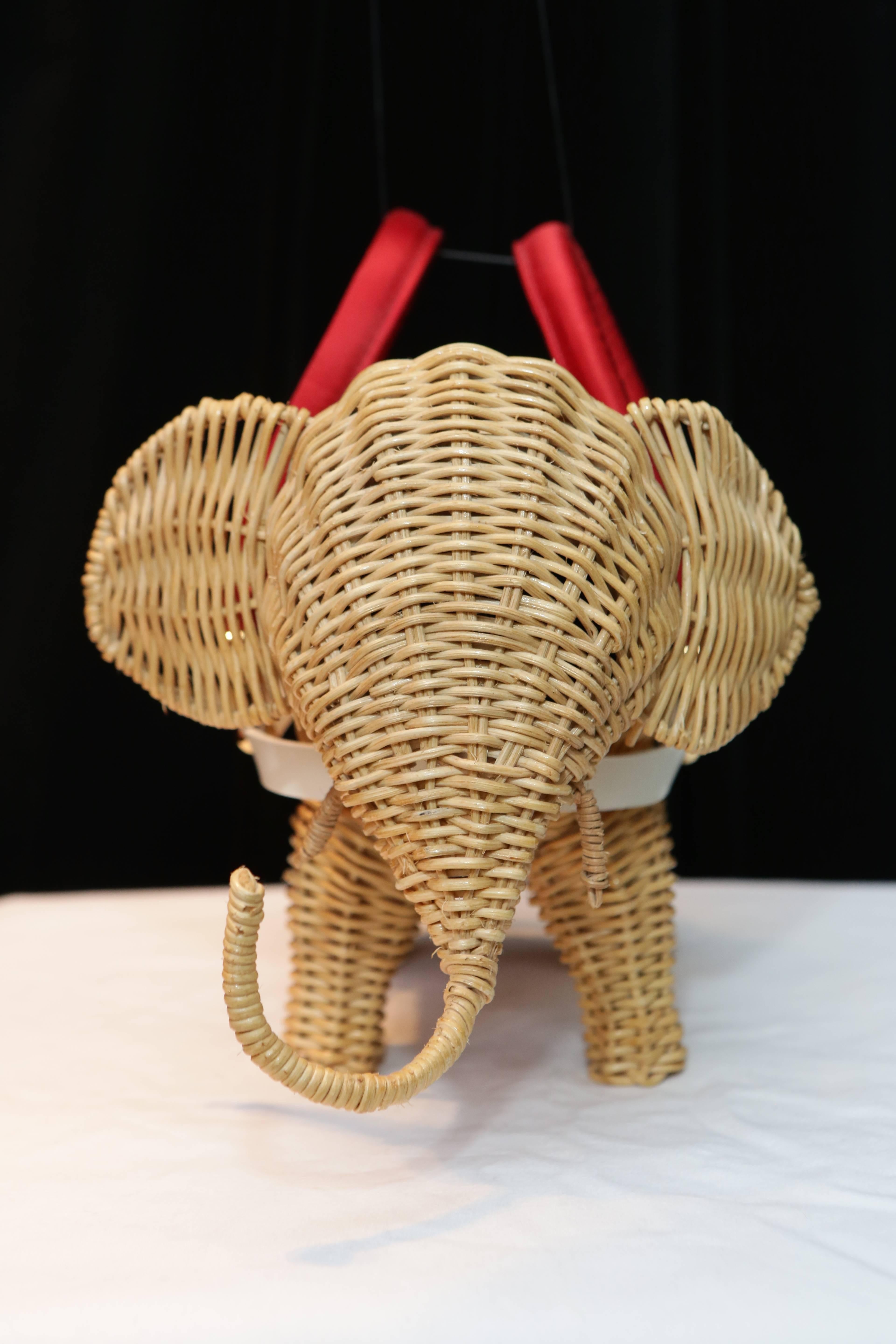 CHRISTIAN LACROIX. A very original handbag made of wicker in a shape of an elephant. 

Removable armor in white leather, connected by gold metal fasteners chiselled with the initials of the brand that hold two handles covered with red satin.