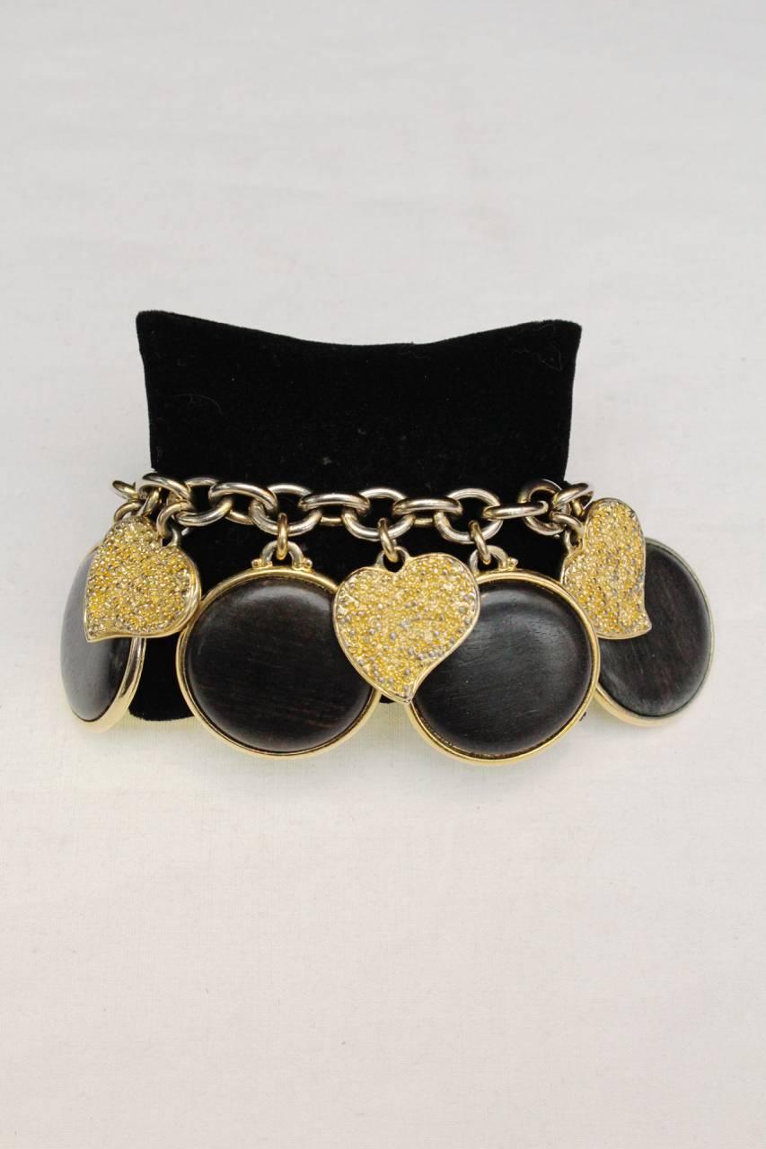 YVES SAINT LAURENT (Made in France) Gilt chain bracelet holding large round gild pendants paved with brown wooden medallions and smaller textured gilt pendants in the shape of stylized hearts. 

Signed on the fastener. 

Good general condition