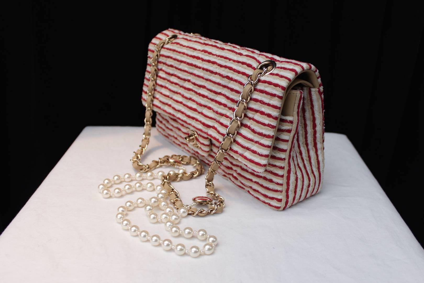 CHANEL (Made in Italy) Timeless model bag consisting of thin stripes of red and ecru cotton and white lace displayed in a pattern of horizontal stripes. 

Gilt metal hardaware including a CC turnlock clasp and a sliding chain handle interlaced