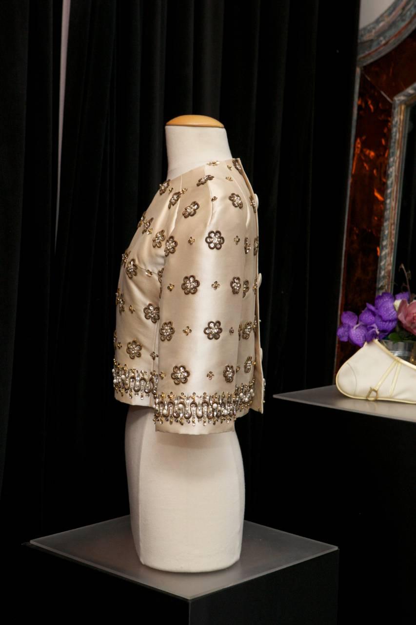 MADELEINE DE RAUCH PARIS Beautiful short blouse/jacket in ecru silk crepe embroidered all-over with flowers in brown woven and decorated with rhinestones, crystals, imitation pearls of different sizes and silvered sequins.

The blouse, which