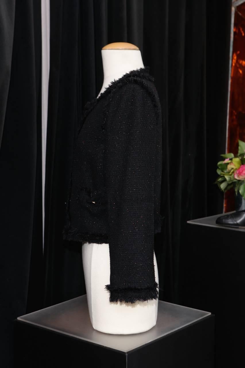 CHANEL (Made in France) Short black jacket with round neck in wool blended with polyester and cotton tweed. 

The piece is entirely embroidered with very small copper-colored glass beads giving a slightly iridescent look to the jacket. 

Black wool