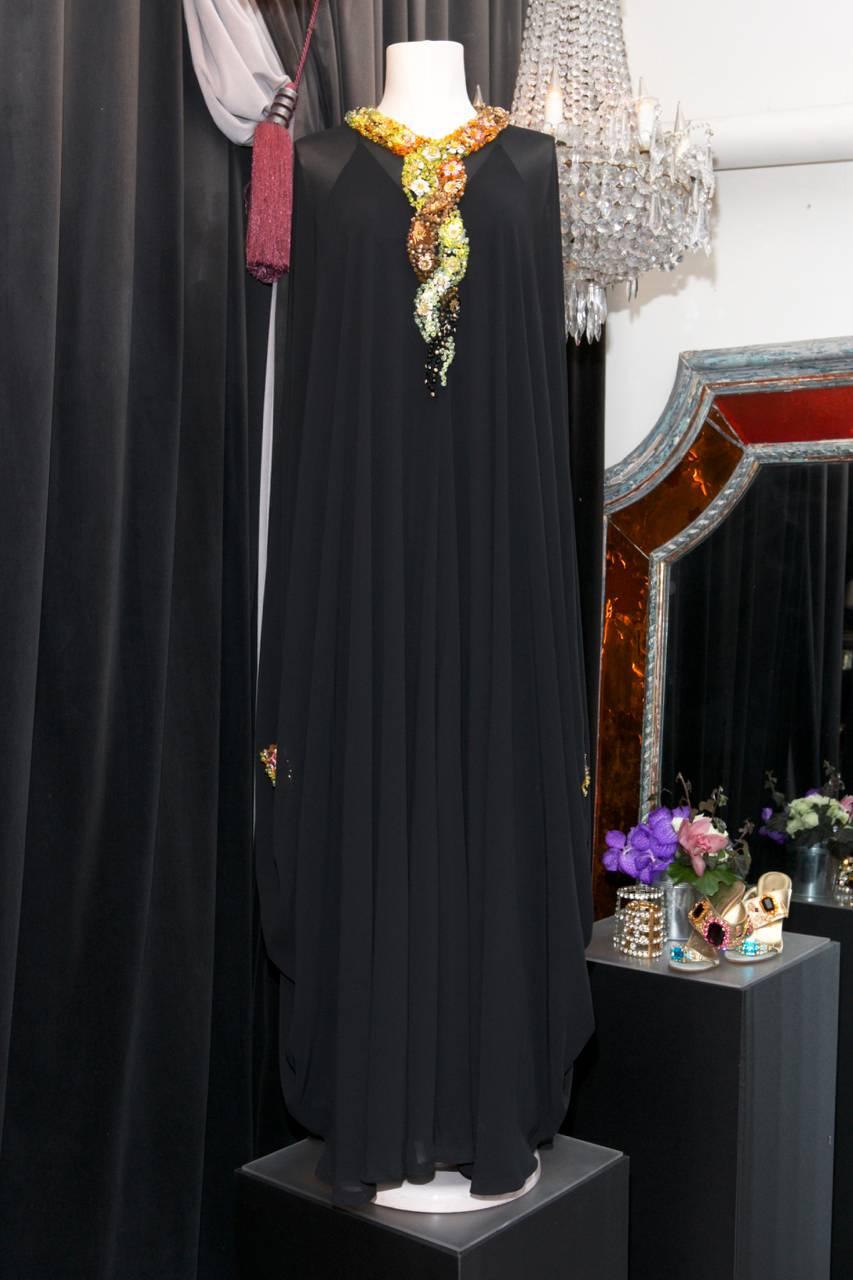 LORIS AZZARO PARIS (Made in France) Iconic 1970s black chiffon caftan embroidered with Rhodoïd and plastic beads in shades of green, orange, transparent, black, brown and gold; forming a floral motif on the collar and cuffs. 

The caftan comes with