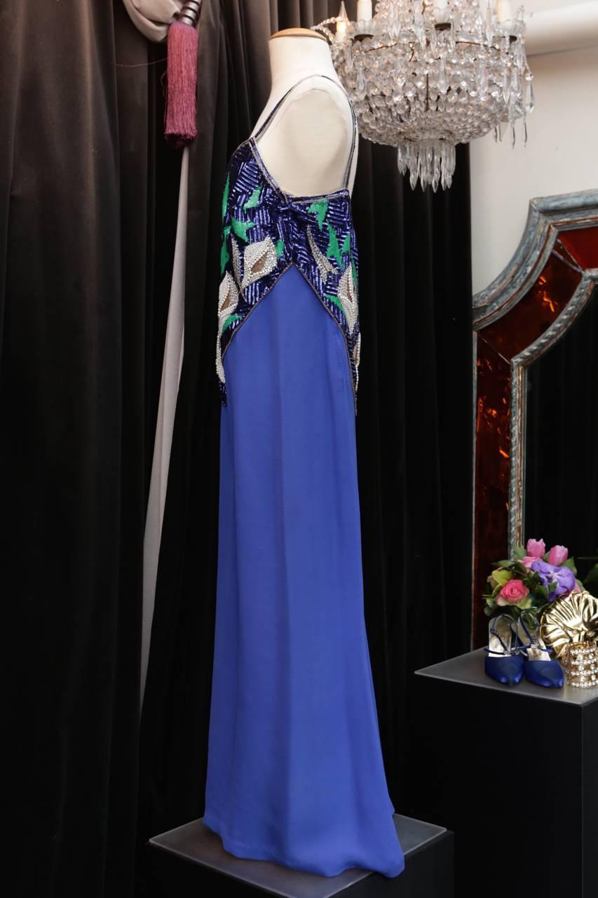 PIERRE BALMAIN PARIS Evening dress in electric blue viscose with thin straps whose bustier is entirely embroidered with faux pearls, green and electric blue sequins, and tubular copper color beads in a vegetal motif. 

Zip on the right side. 

Lined