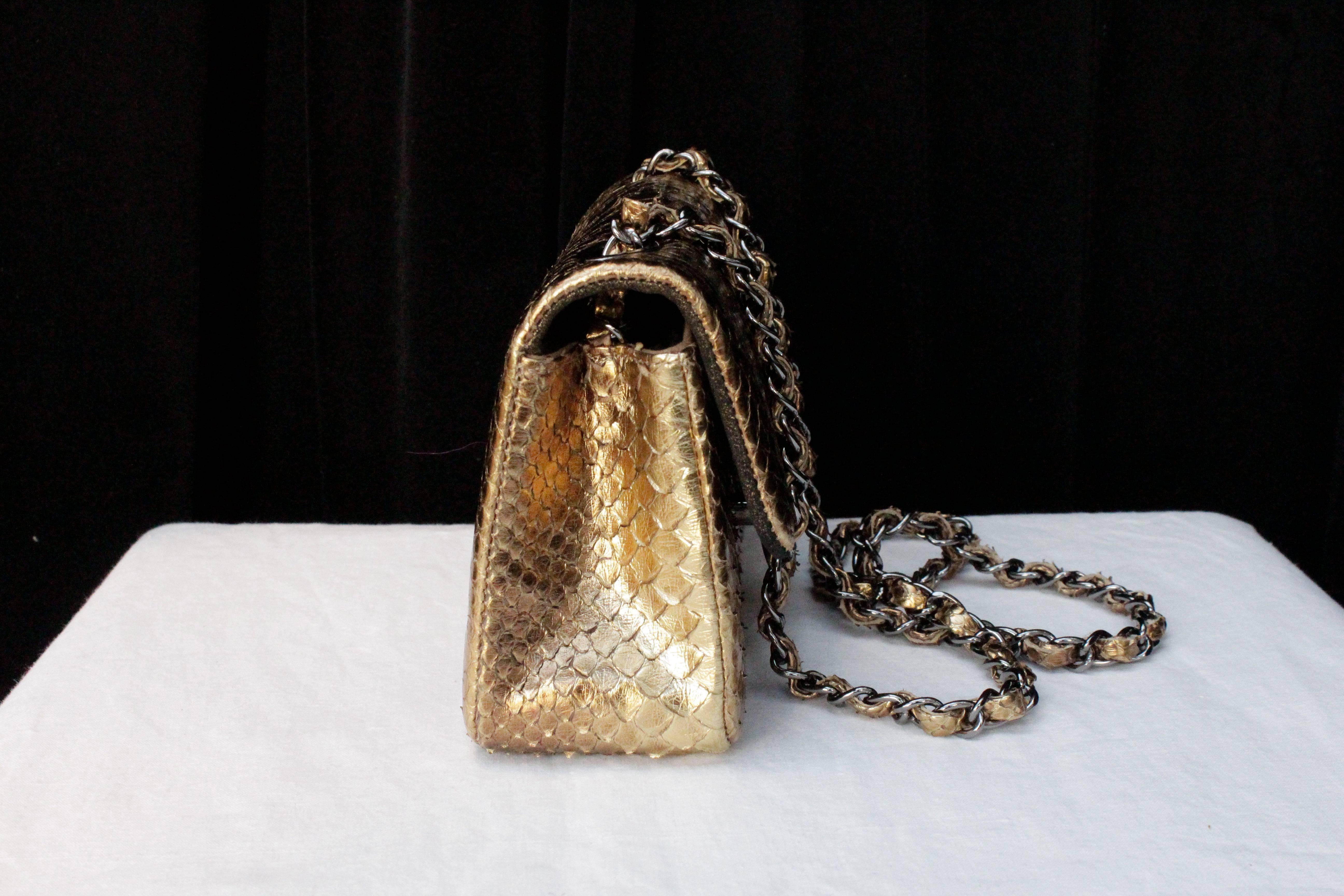 CHANEL (Made in France) Small evening bag small (Timeless model) covered with gold-colored with copper shades snakeskin. Flap with CC turnlock in silvered metal. 
Non-sliding metal silvered chain interlaced with snake-covered leather link. 

Flap