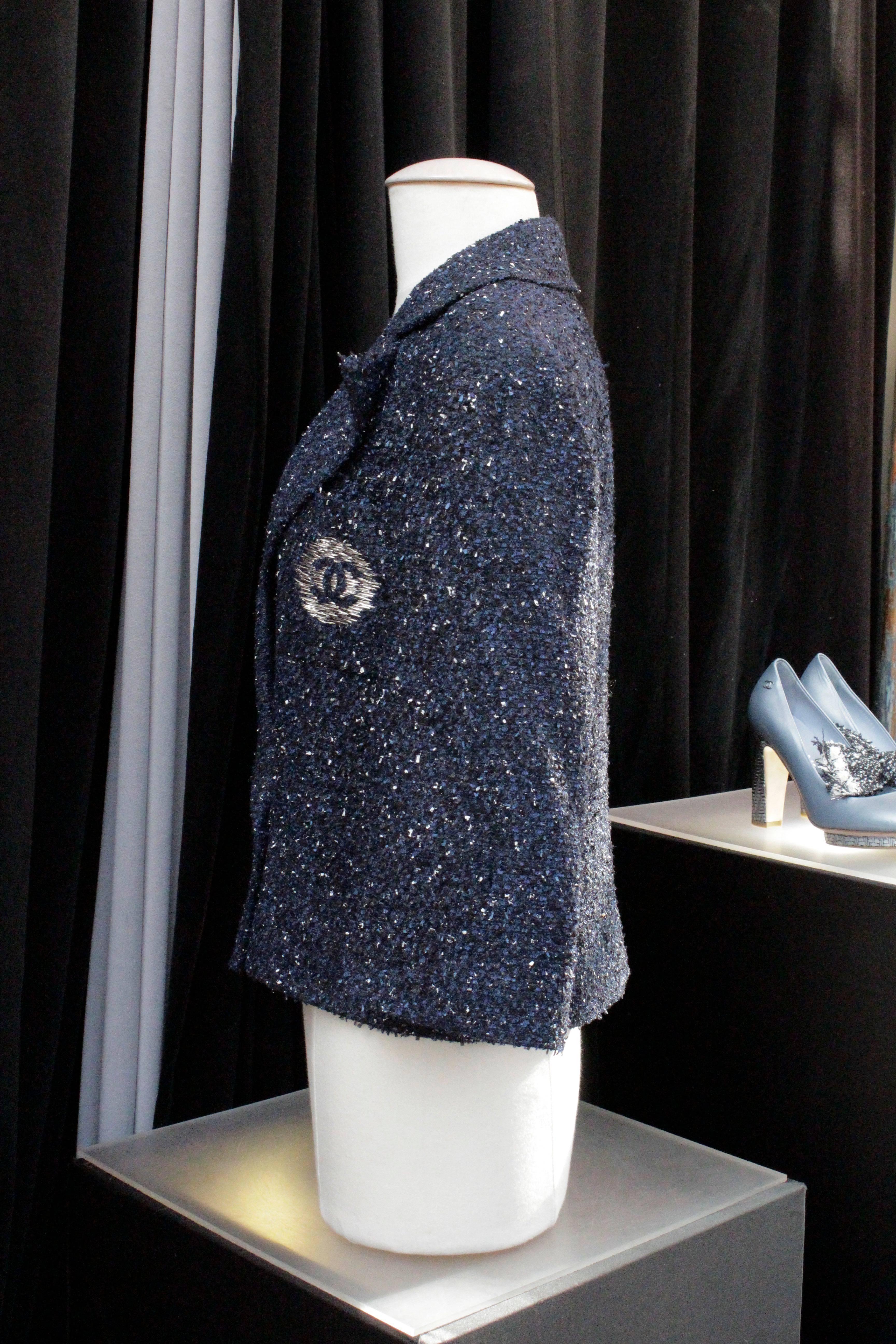 CHANEL (Made in France) Coll Ready to Wear Spring 2012. 

Small three-quarter wide sleeves tweed jacket in navy blue and black threads painted in white. 
Front buttonhole with two engraved silver metal buttons centered with a CC. 

Trompe l'oeil
