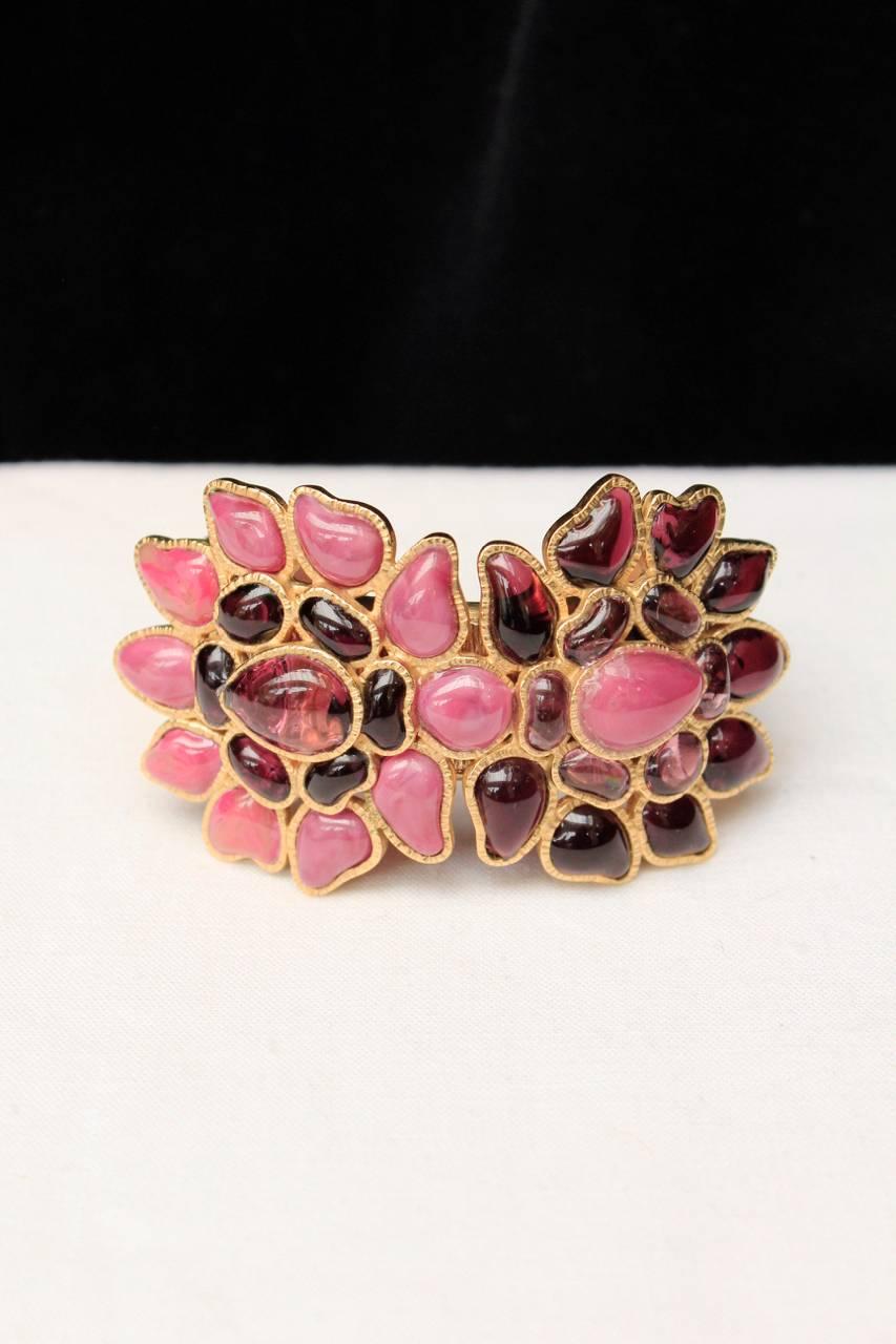 CHANEL (Made in France) Fantastic and rare gilt bracelet featuring two flowers in pink and purple enameled glass. 
The inside of the bracelet is also covered with enameled glass. 
Signed on a plaque on the inside. 

Collection Fall 2007.

Excellent