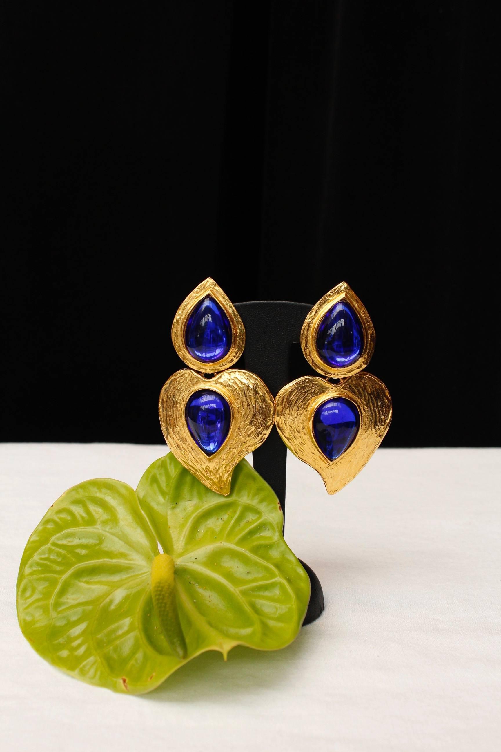 YVES SAINT LAURENT (Made in France) Drop articulated clip-on earrings in gilded metal. They are composed of a tear-drop and a stylized heart, each of them paved with a blue resin cabochon. Signed at back.

Circa 1980-1990.

Total length 8 cm (3.25