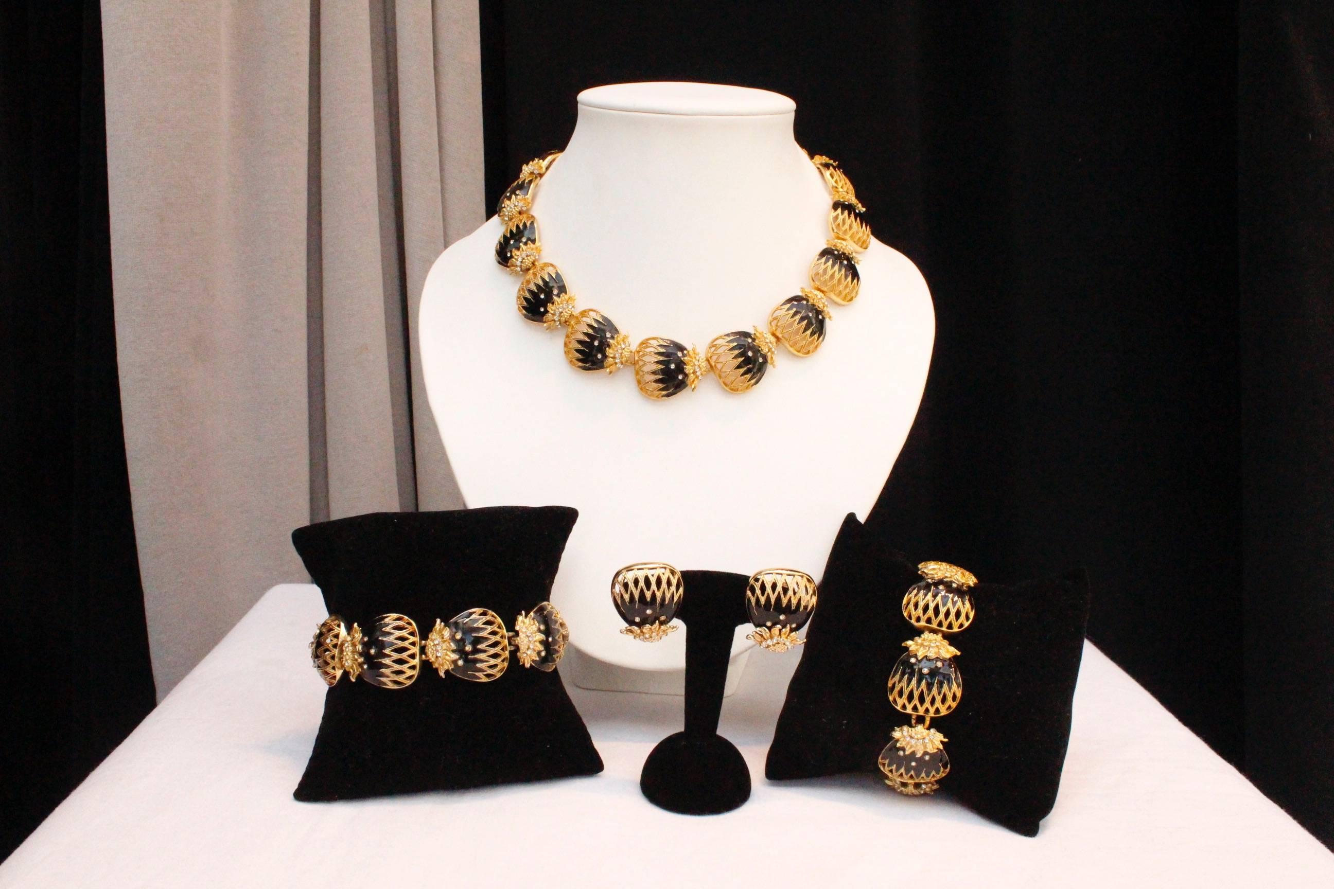 BALENCIAGA (Made in France) Gorgeous parure comprised of a pair of clip-on earrings, a bracelet and a short articulate necklace. Each piece is made of gilded metal elements with black enamel, paved with white rhinestones, representing stylized