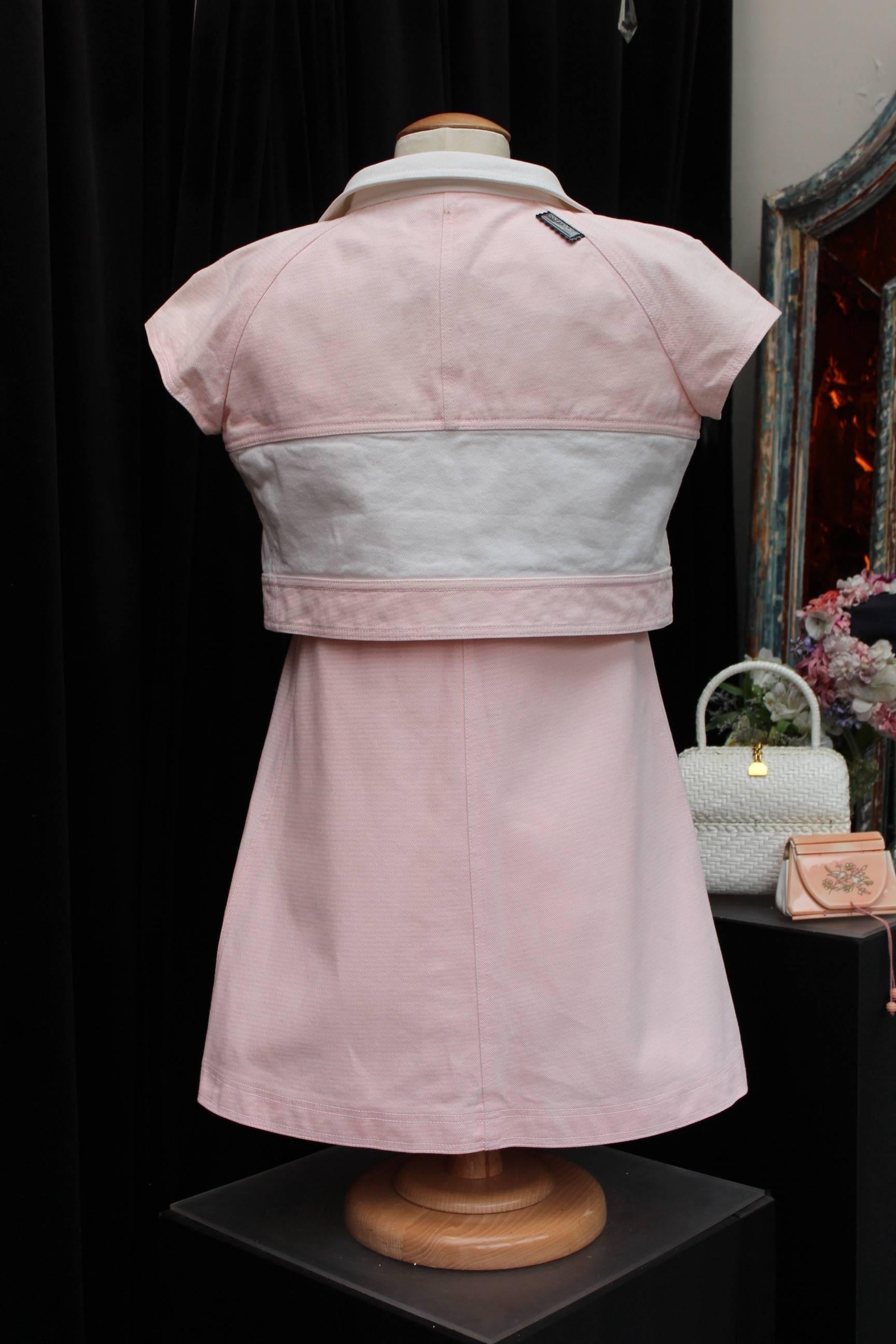 COURREGES (Made in France) Adorable set comprised of a three-hole dress and a short jacket with short sleeves. The set is made of white and light pink cotton. The flared dress with patch pockets is knee-high. It closes with a white zip on the left
